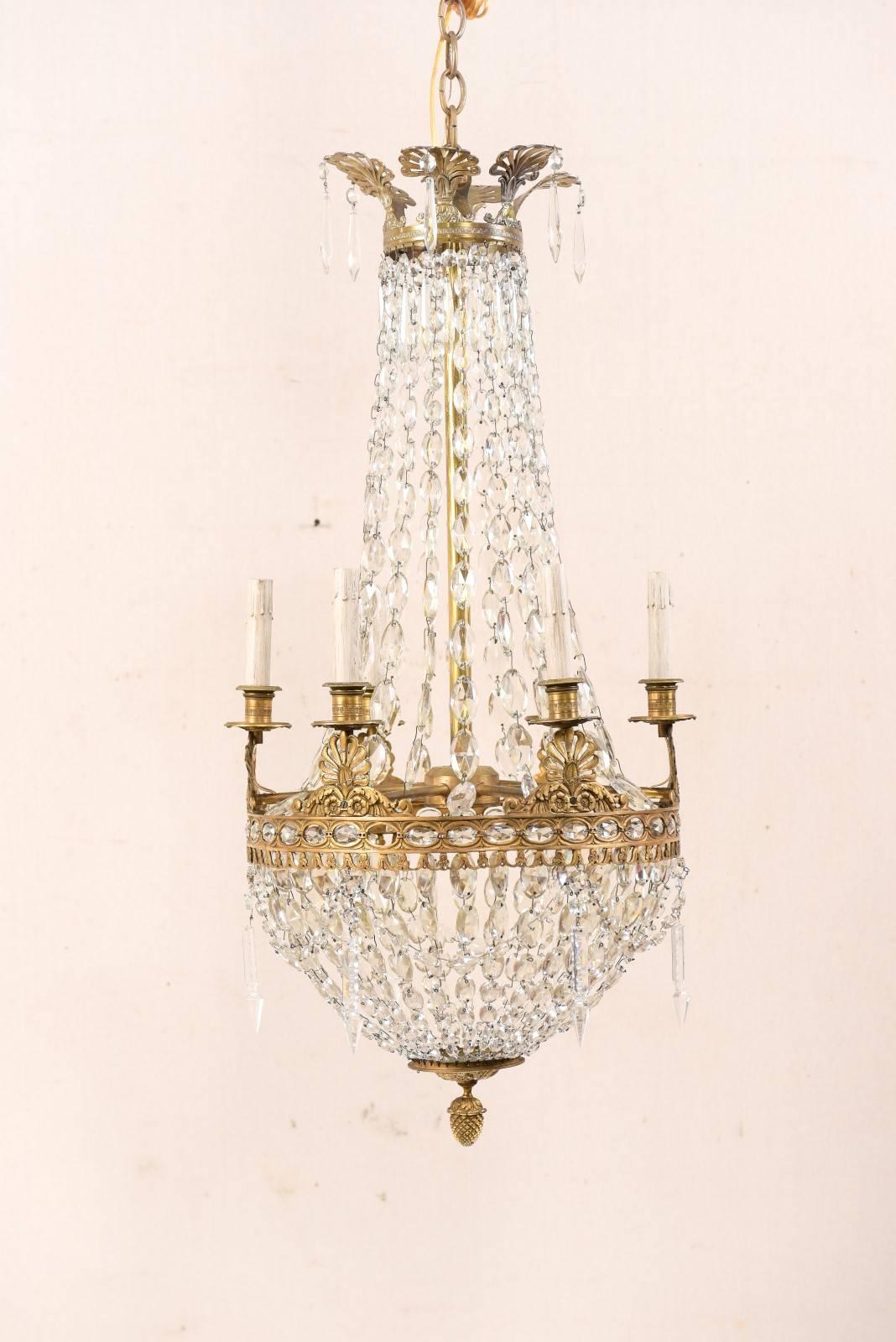 An elegant Italian mid-20th century six-light crystal basket chandelier. This vintage chandelier from Italy features a basket design shape decorated in strands of crystals, draped throughout the body. The upper brass corona with anthemia projects