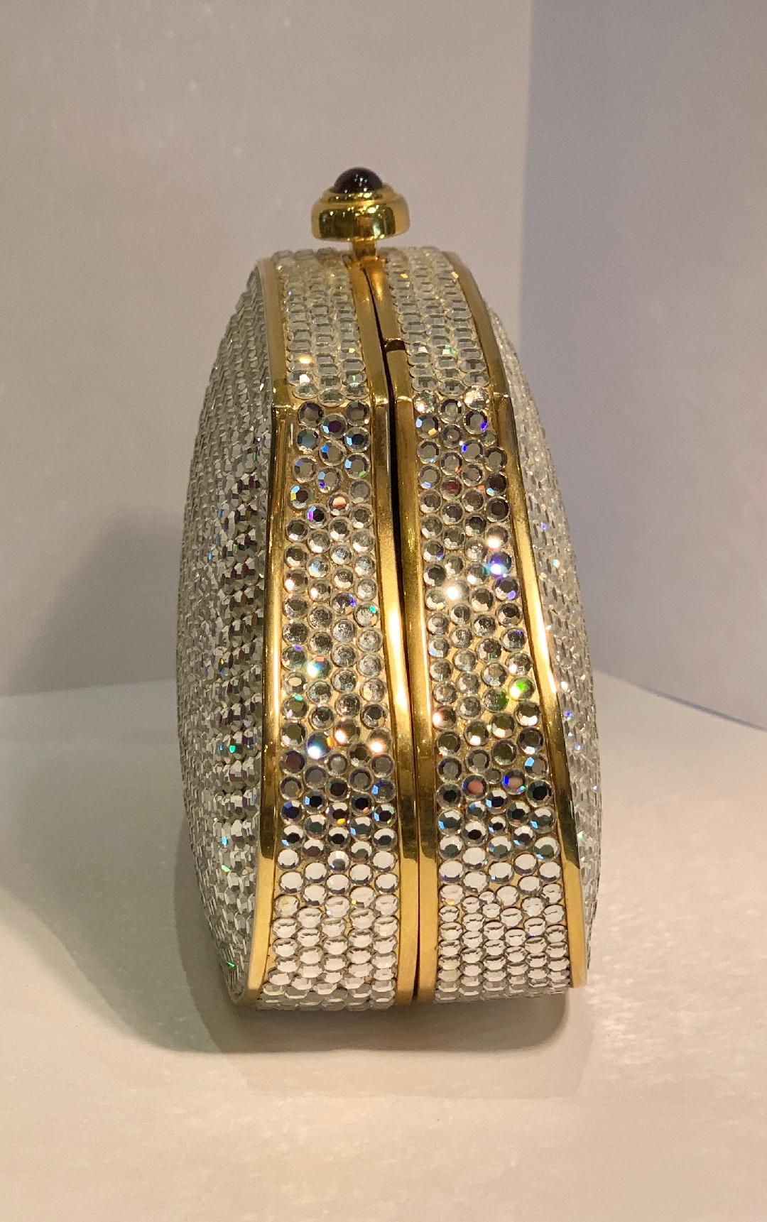 Exquisite couture designer, Judith Leiber, hand made clear crystal minaudiere or evening bag with gold metal frame features a gold metallic leather interior and a gold toned metal chain shoulder strap which tucks inside. Tons of handset silver