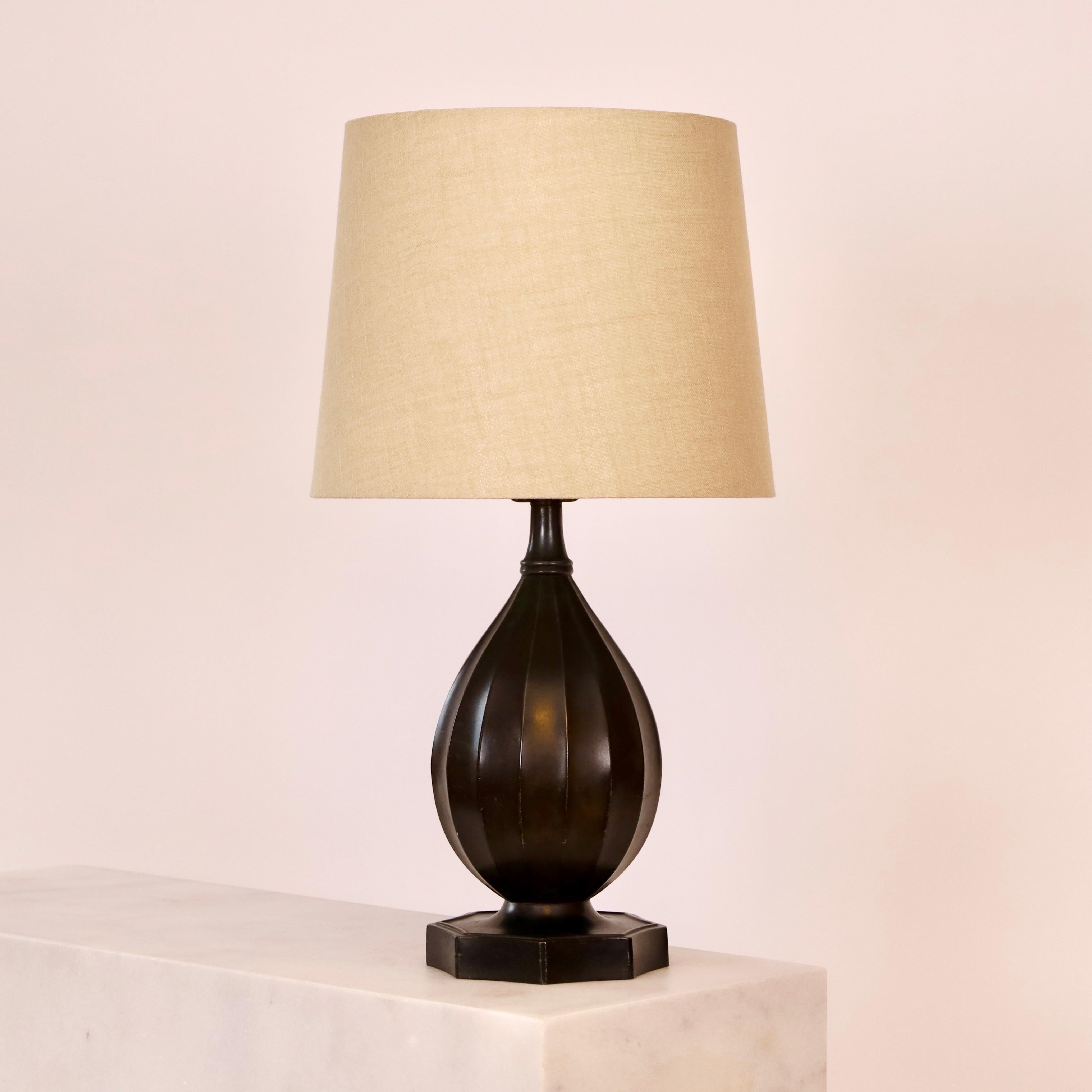 Une lampe de table intemporelle de Just Andersen en 1936 dans un rare bon état. Une pièce maîtresse pour une belle maison.  

* Lampe de bureau en métal en forme de bouteille avec des lignes verticales et un abat-jour en tissu beige.
* Designer :