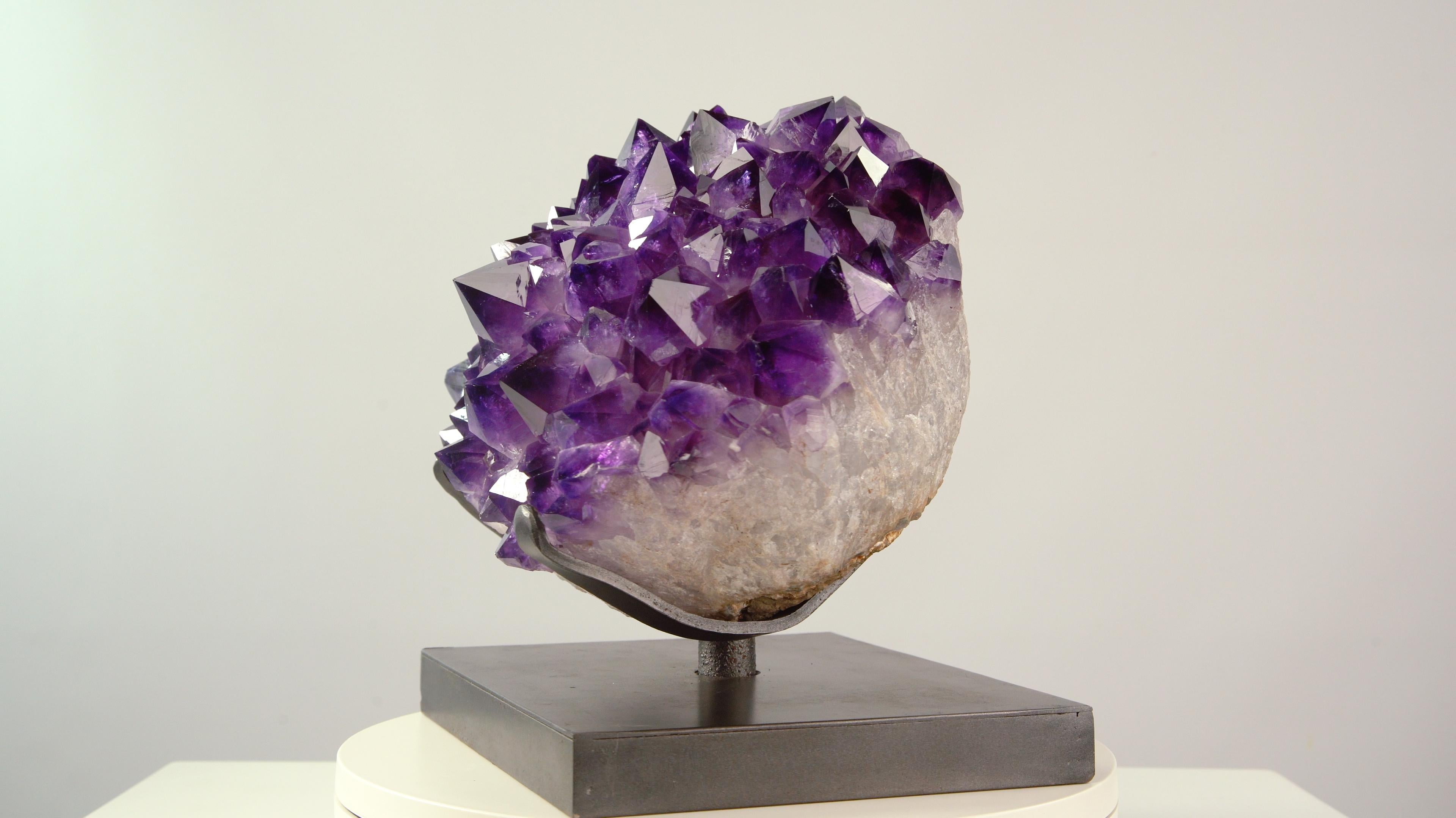 Extracted from a geode of unusually large and bright purple amethyst, this block contains beautifully formed and pristinely preserved crystals in a pleasing convex arrangement. The deep purple colour contrasts wonderfully with the white quartz
