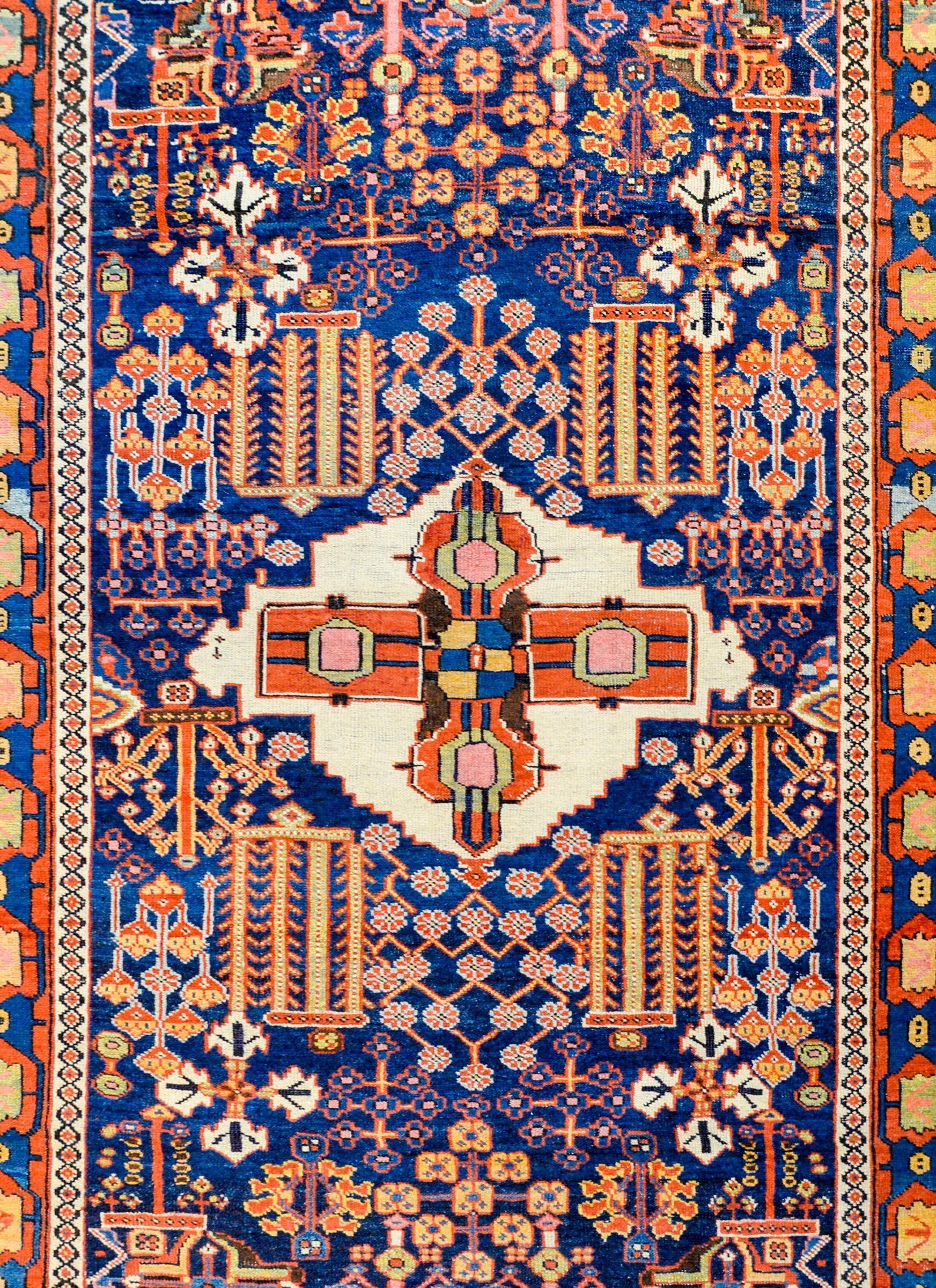 An exquisite late 19th century Azari rug with a fantastic bold tribal pattern containing a large central medallion with stylized flowers on a white background, amidst a field of mirrored myriad flowers and branches on a dark indigo background. The