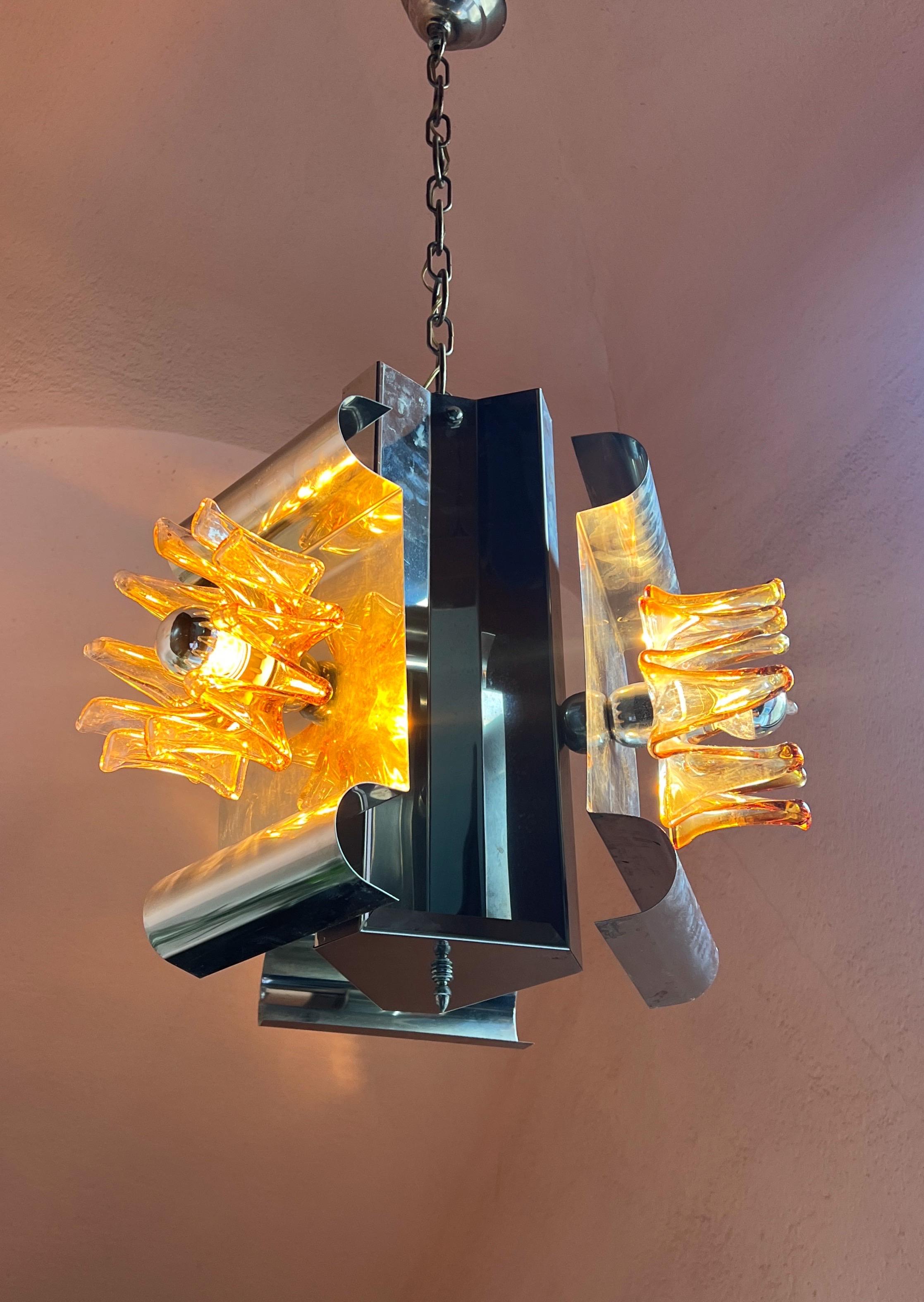 Squisita lampada a sospensione Mazzega Murano di Carlo Nason. 

Questa splendida lampada a sospensione presenta tre paralumi in vetro a forma di fiore in un'armoniosa miscela di tonalità trasparenti e caramello, che creano una luce calda e