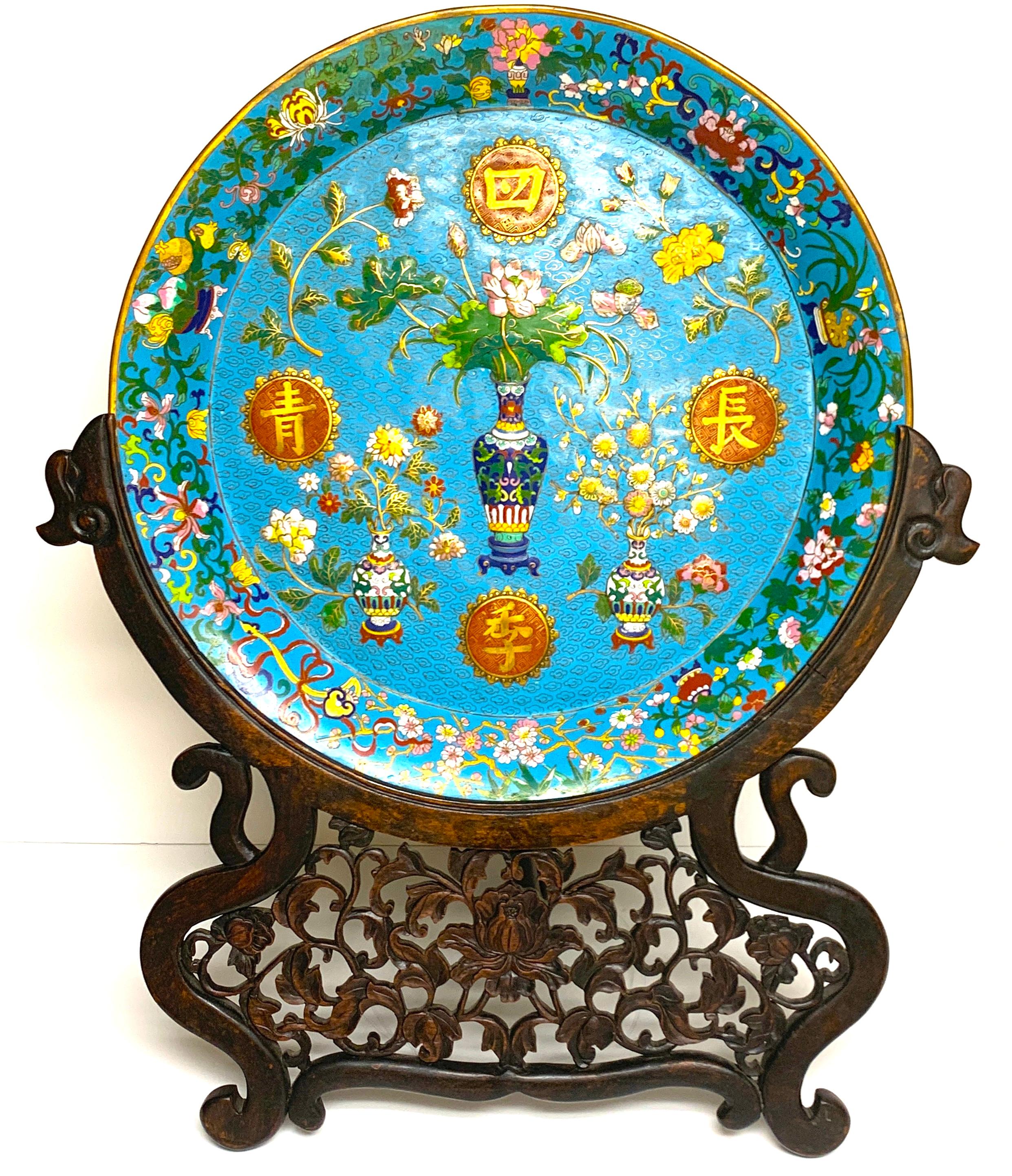 Exquisite Ming style Cloisonné charger and stand, profusely decorated front and back. The front with three dimensional (blown out/ raised) vases with flowers and four applied Chinese characters. The back vases and planters with Cherry blossoms and