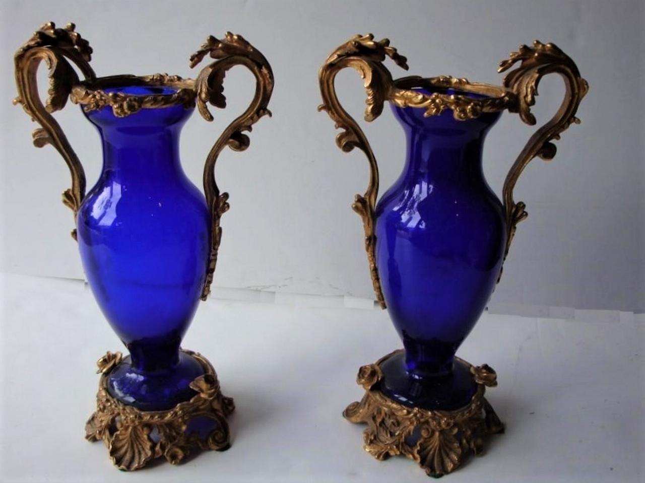 L'article suivant est une paire de rares vases centraux néoclassiques du XIXe siècle en verre bleu cobalt et bronze, avec des poignées et un bord en fleurs et des bases en volutes avec des fleurs et des coquillages. Ces magnifiques pièces ont été