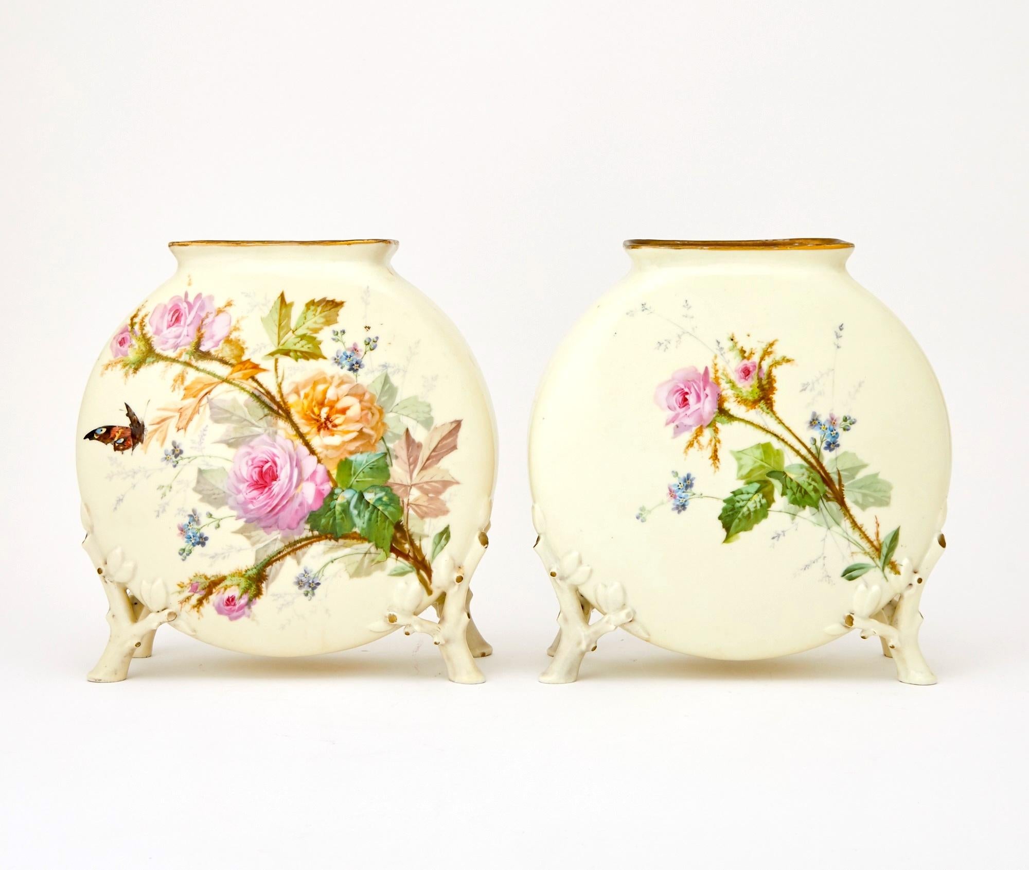 Cette paire exquise de vases anciens en porcelaine peints à la main témoigne d'un art remarquable et d'un charme délicat. Chaque vase présente un extérieur magnifiquement peint, orné de roses, de fleurs et de papillons, dans des teintes douces et