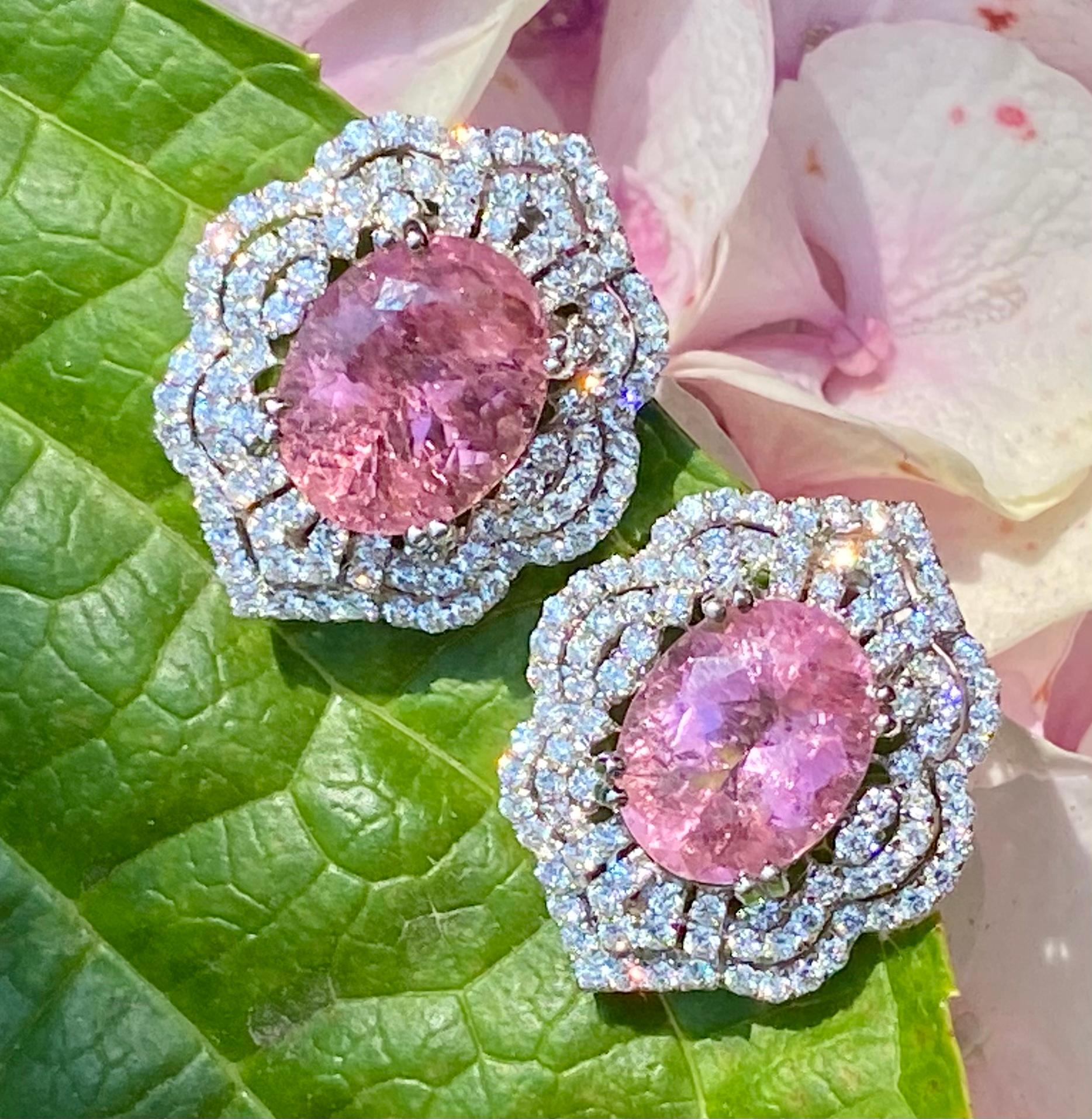 Exquisite pair of estate, oval shaped faceted pink tourmalines are talon prong set in 18 karat white gold and surrounded by approximately 3.00 carats of round brilliant cut diamonds in a beautiful openwork scalloping design. Earrings are for pierced