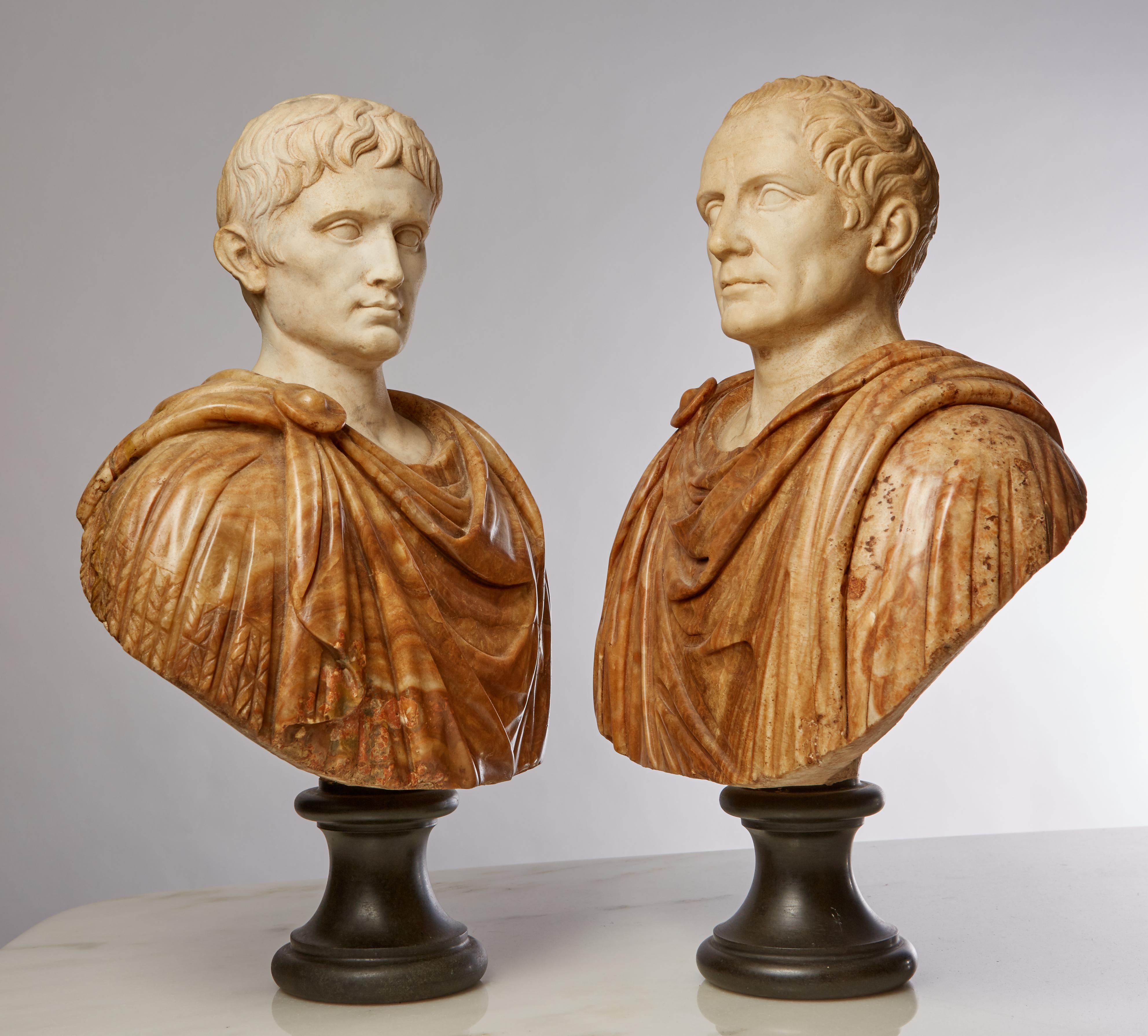 An exquisite pair of 19th century Grande Tour marble busts of the Roman Emperors Caesar Augustus and Diocletian molded in the ancient style. Rising from black marble bases, their bodies draped in flowing togas, fastened at the neck with the Imperial
