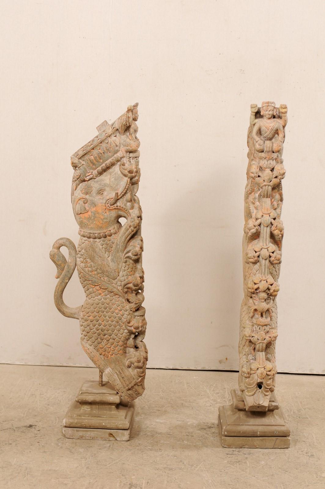 An exquisite pair of hand carved Hindu wooden temple struts, mounted on stone bases, from the 19th century. This pair of antique temple struts from S. India are magnificently carved with depiction of a scaled elephant kneeling serenely on a tower of