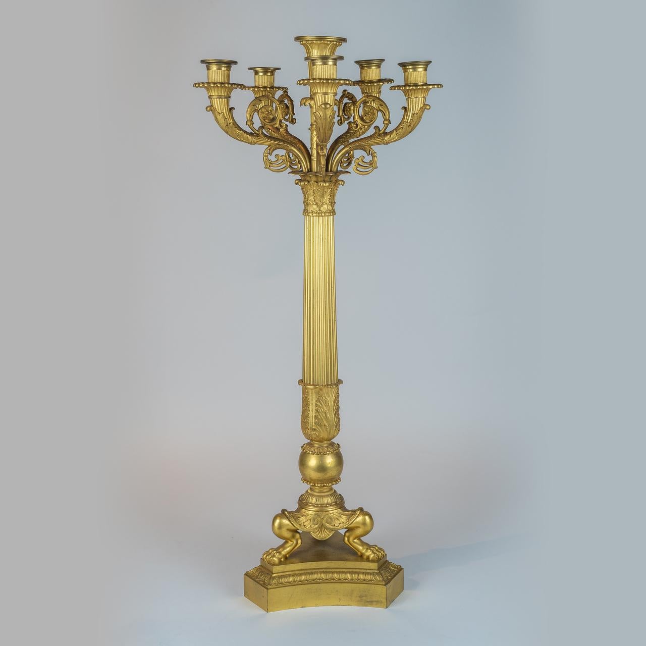 The candelabras are raised on fluted columns which terminate in finely chased capitals and are supported on a tripartite base raised on lion paw feet and mounted to a conforming platform base.

Origin: French
Date: circa 1825
Dimension: 27 in