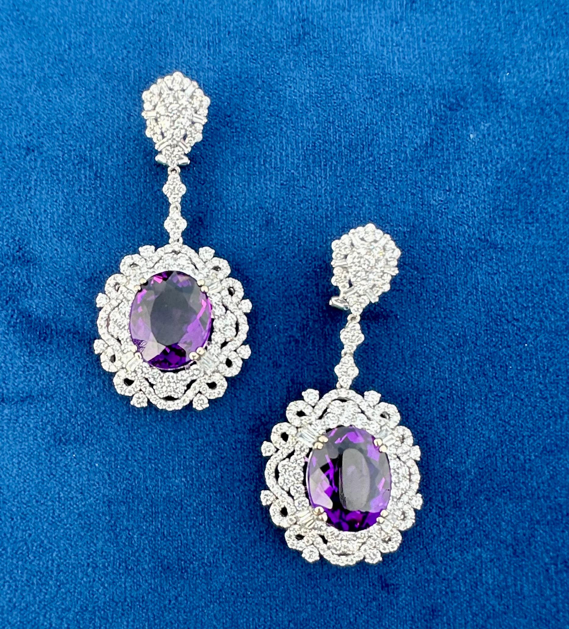 A very exquisite pair of very sparkly in real life, approximately 42.49 carat natural intense purple Brazilian amethyst and diamond earrings are set in 18 karat white gold and are comprised of approximately 354 round brilliant and baguette cut