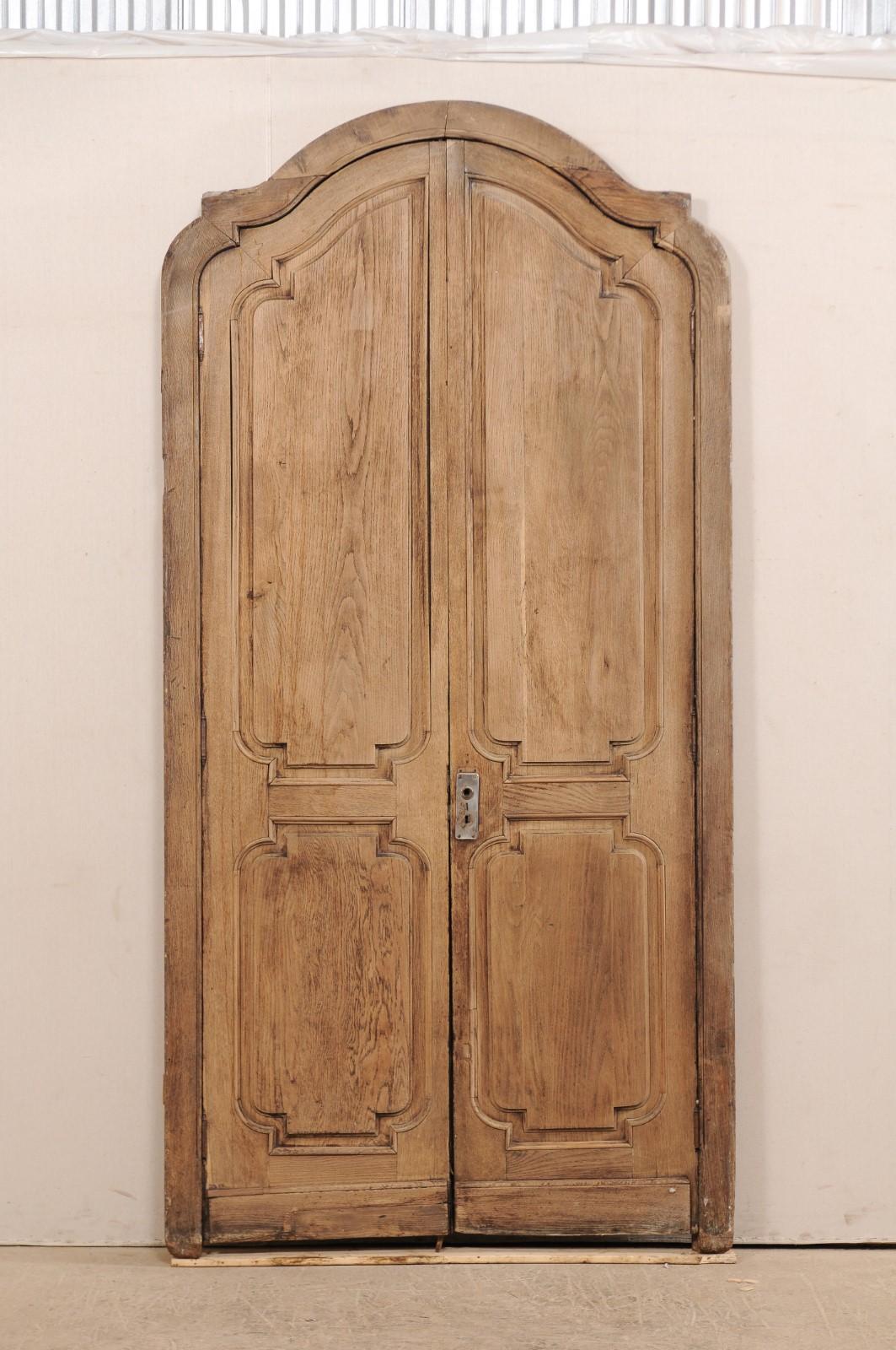 An exquisite pair of Spanish arched double doors with their original casing from the 19th century. This fabulous piece consists of two antique Spanish doors with their original casing. The surround or casing has a depressed arch pediment with eared