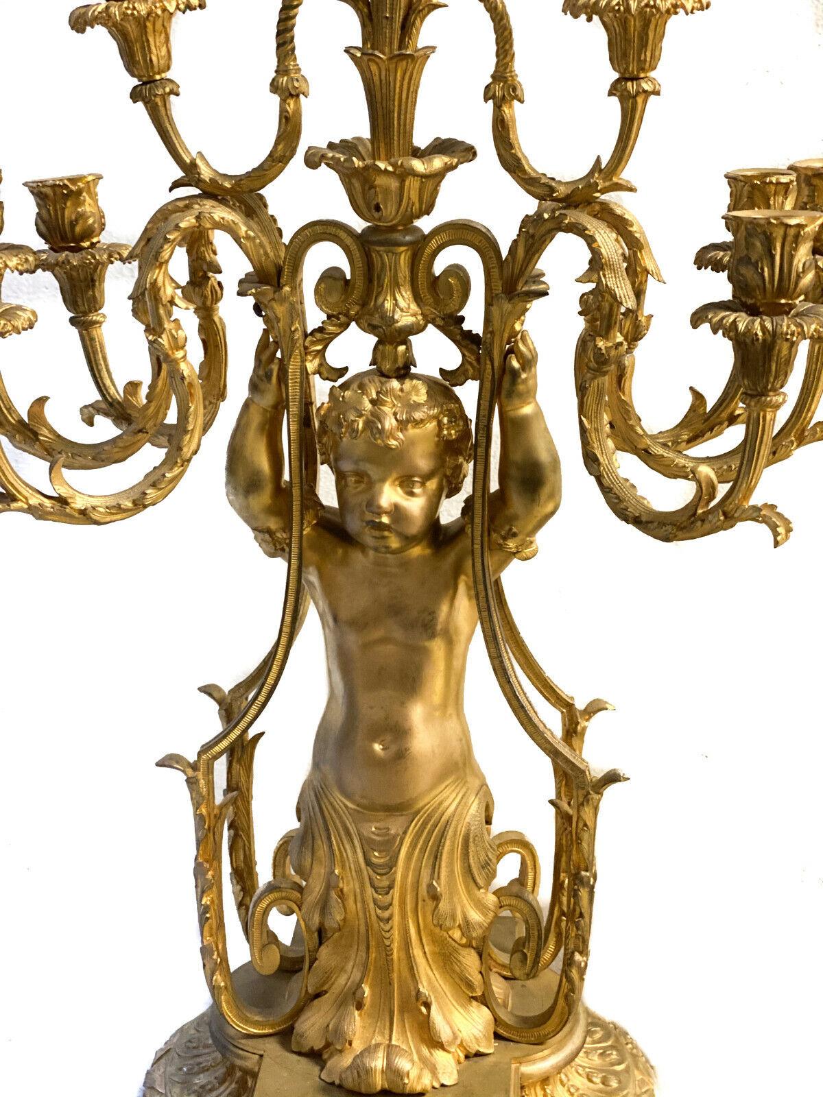 Exquisite pair of French gilt bronze 9 arm figural candelabras, Napoleon III

An exquisite pair of French gilt bronze 9-arm figural candelabras, Napoleon III circa 1860. Each candelabra depicts a figural putti holding up leaf-molded brackets,