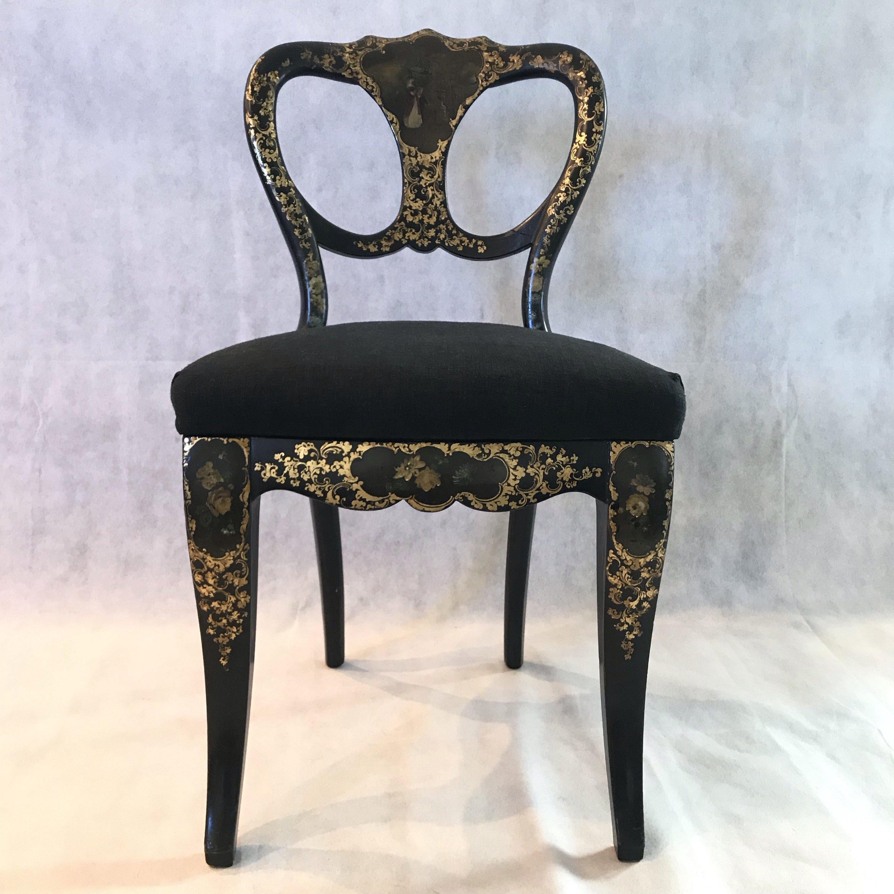 Elegant pair of French 19th century ebony hand painted papier mâché chairs having black backgrounds with intricate fancy gold decoration and newly reupholstered black linen seats. Each back has an original marvelously weathered figural painting.
