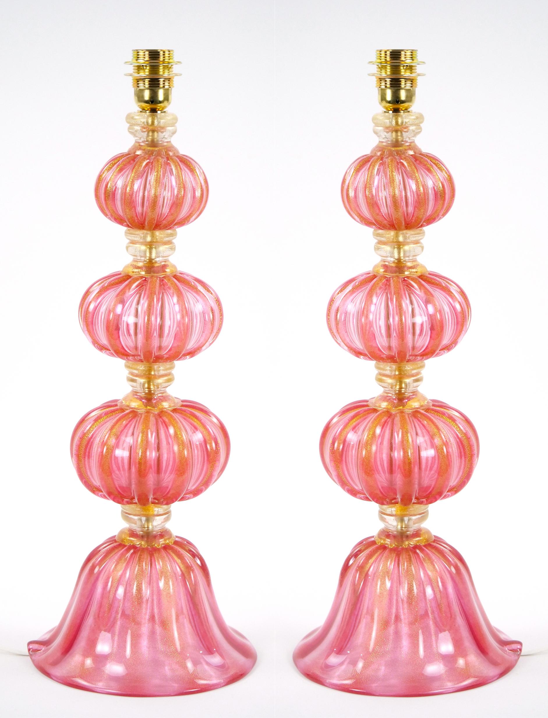 Enhance your interior décor with this exquisite pair of Venetian Murano glass table lamps, painstakingly handcrafted and mouth-blown to perfection. Each lamp features a captivating pink-colored glass base adorned with delicate gold flecks, imbuing