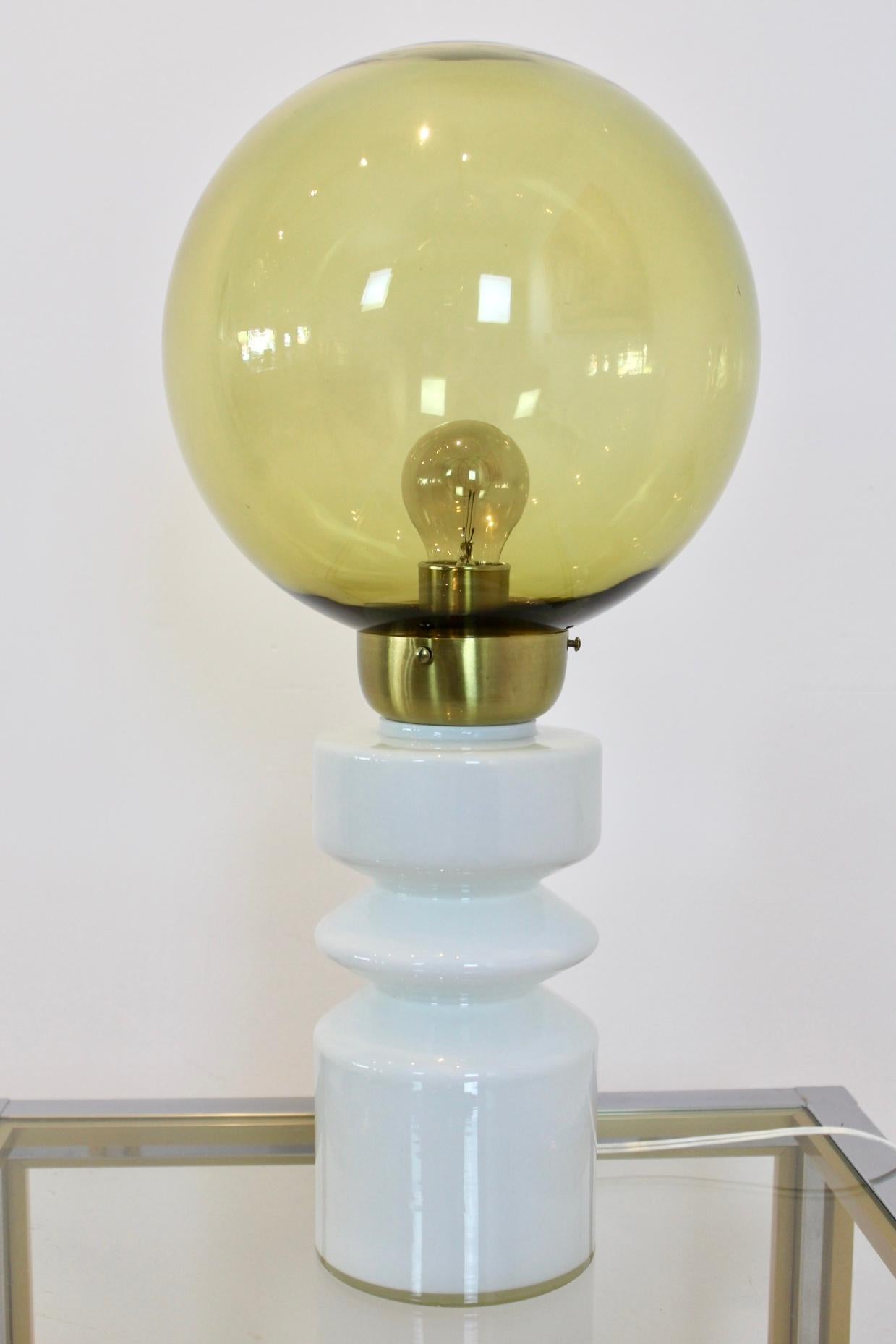 Unique RAAK table lamp in excellent condition. Designed and made by RAAK Amsterdam, Holland. Very rare and beautiful lamp with a white glass base, brass middle part and a smoked glass globe on top. Exquisite large table lamp and iconic Dutch design.