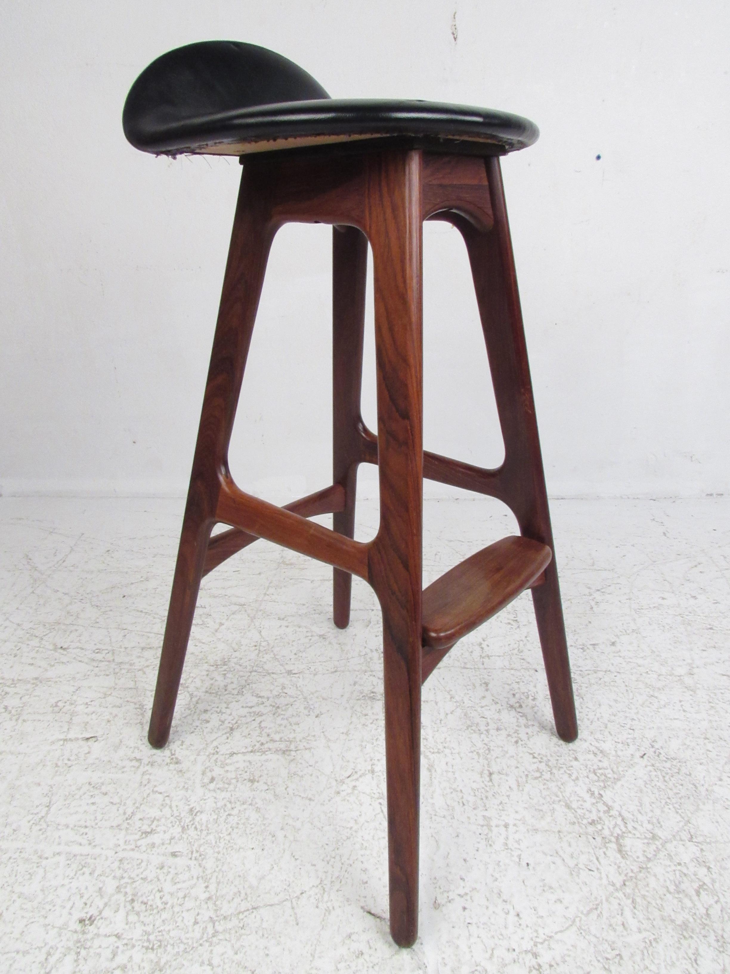 This beautiful set of three vintage modern bar stools feature sculpted rosewood frames and a thick padded seat covered in black vinyl. An iconic Danish design by Erik Buch that provides optimal comfort without sacrificing style. The Sleek contoured