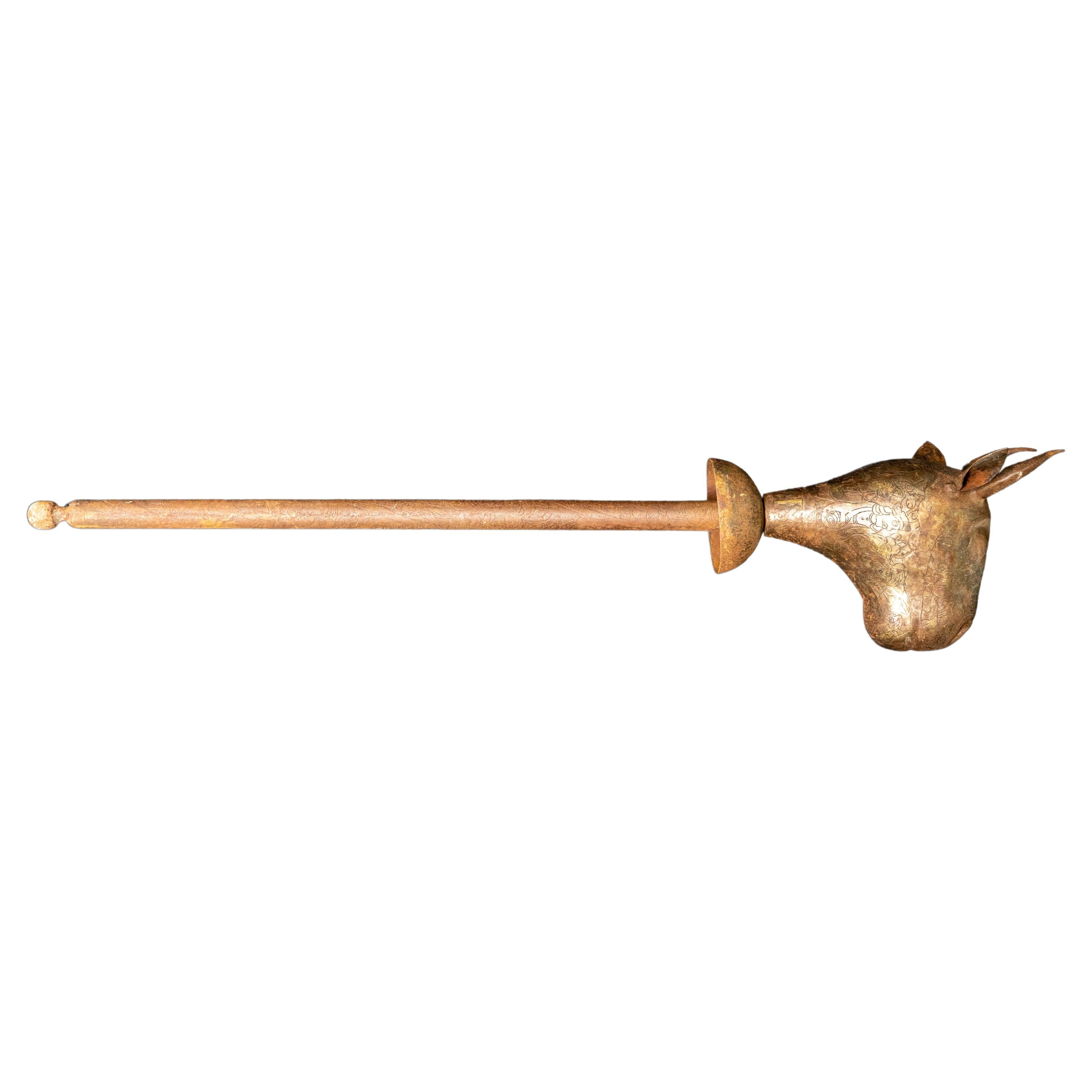 Ce bâton de cérémonie Qajar à tête de taureau du XIXe siècle est un artefact remarquable qui témoigne de l'artisanat exquis et de la finesse artistique de la dynastie Qajar. Fabriqué en acier, ce bâton de cérémonie présente des gravures complexes