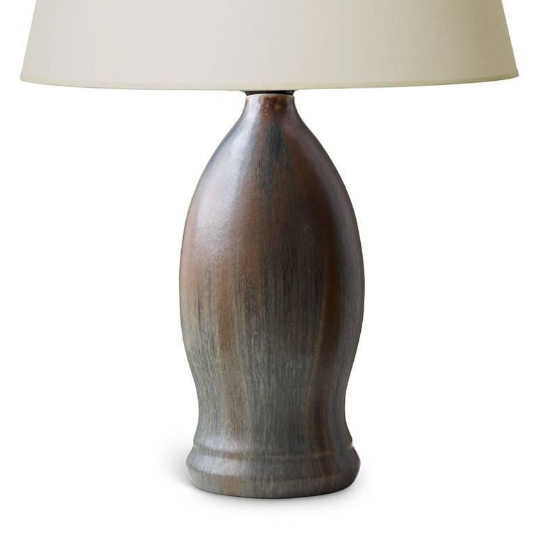 Exquisite table lamp by Patrick Nordström for Royal Copenhagen with a sinewy oval body on a gracefully flaring base, in stoneware with a rare and very attractive glazing effect, with gossamer strokes of cognac-tan over charcoal-green, with original