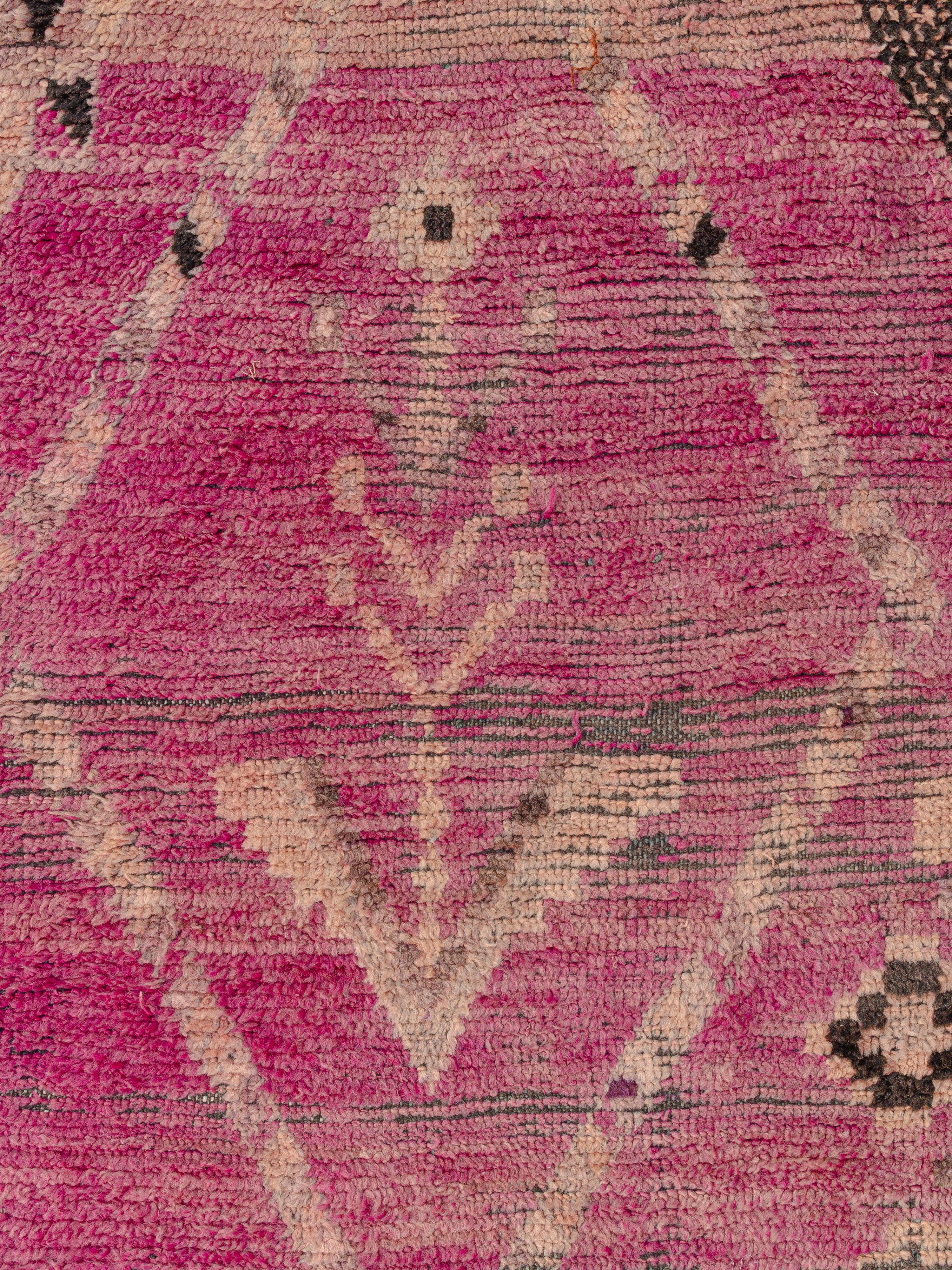 An intriguing carpet from the plains region southwest of Marrakech full of character and a well loved patina. Two opposing double axe motifs near the center of the composition reflect a harmony between male and female symbology. They are flanked by