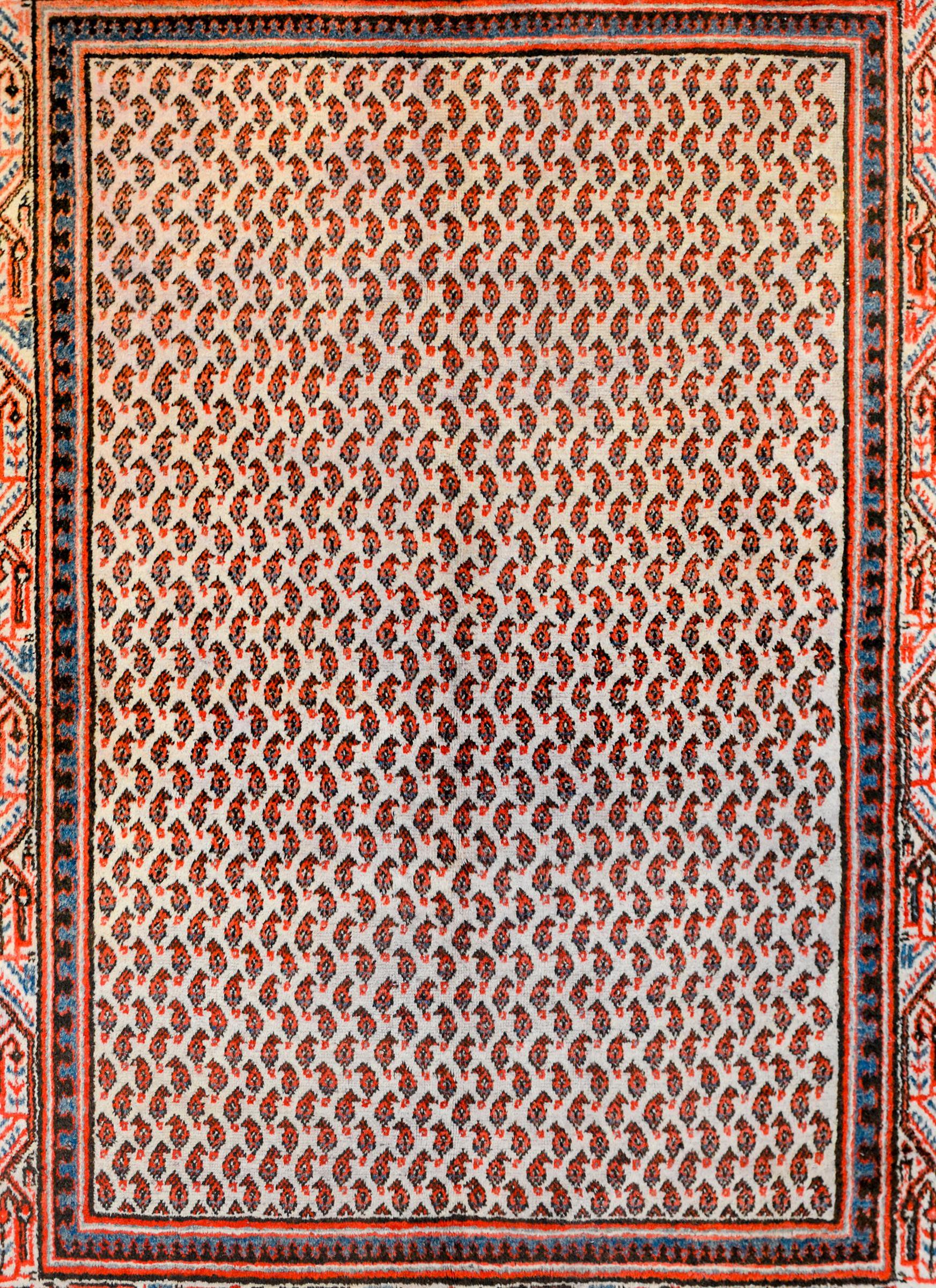 An exquisite vintage Persian Seraband rug with a beautiful all-over paisley pattern rendered in crimson, coral, and indigo, on a white colored background. The border is beautiful, with a stylized floral and willow tree pattern flanked by matching
