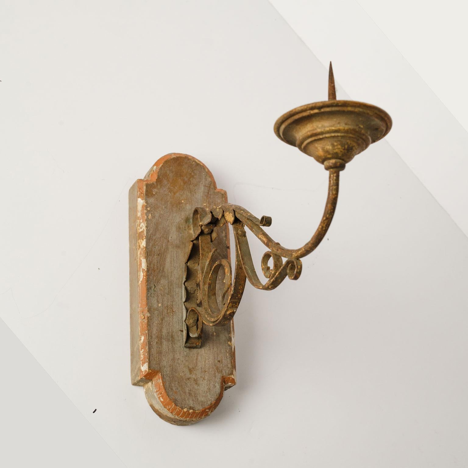 Exquisite wood and iron sconce with single arm. Beautiful original (or early paint) paint over gesso applied over surface of wooden back. Back is hand carved. Single forged iron arm decorated with hammered scrolling acanthus detail. Remnants of old