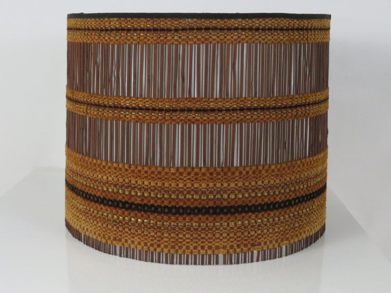 Designed by Maria Kipp, this large restored woven lamp shade is the epitome of her work featuring vertical dark wood slats and horizontally woven chenille strands in shades of brown, black and gold. The interior lining has been entirely replaced