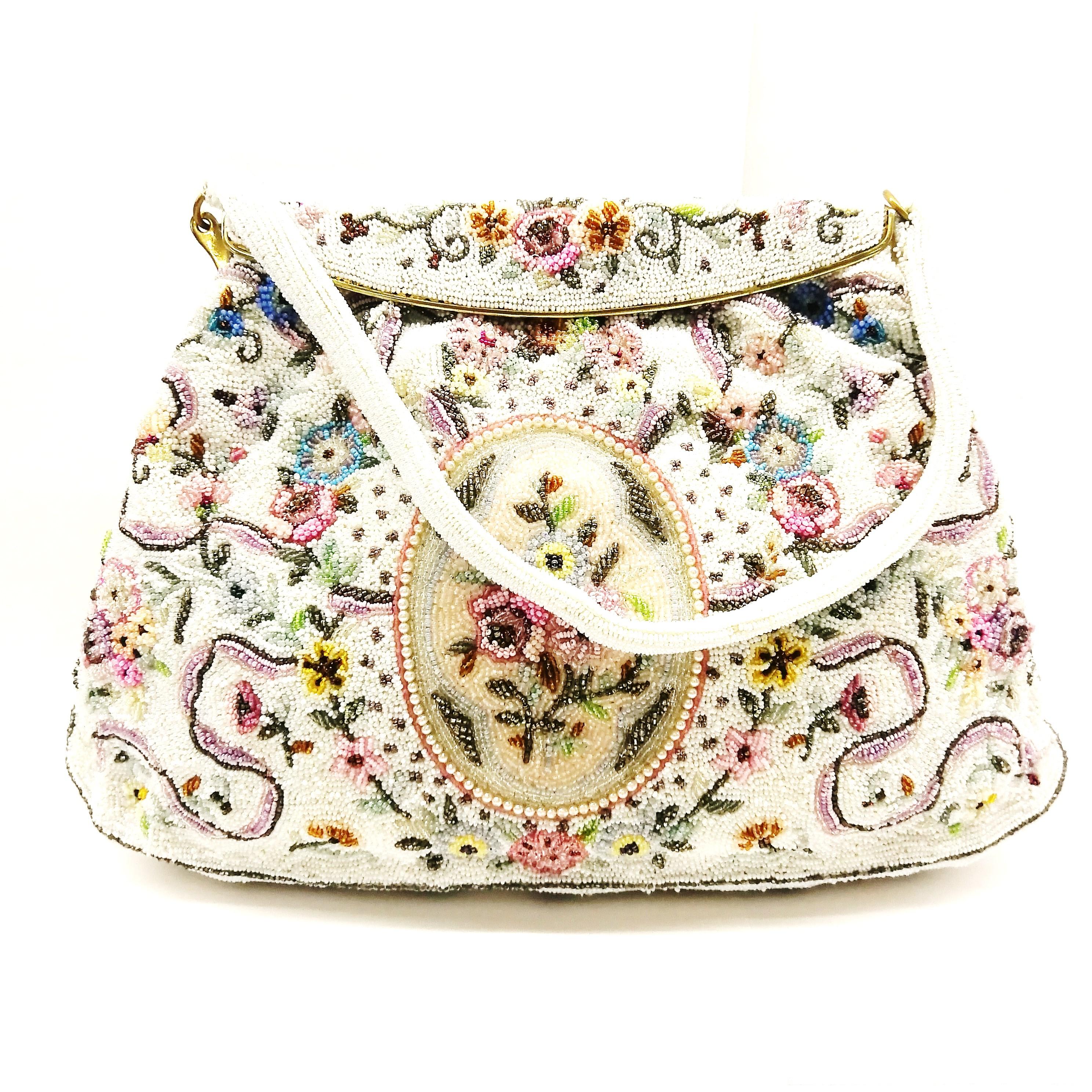 With highly detailed and intricate bead work characteristic of Morabito, this exquisite handbag  is elegant and eye catching. A floral pattern adorns the bag, in a range of delicate colours, sitting against a white background. It has a rigid beaded