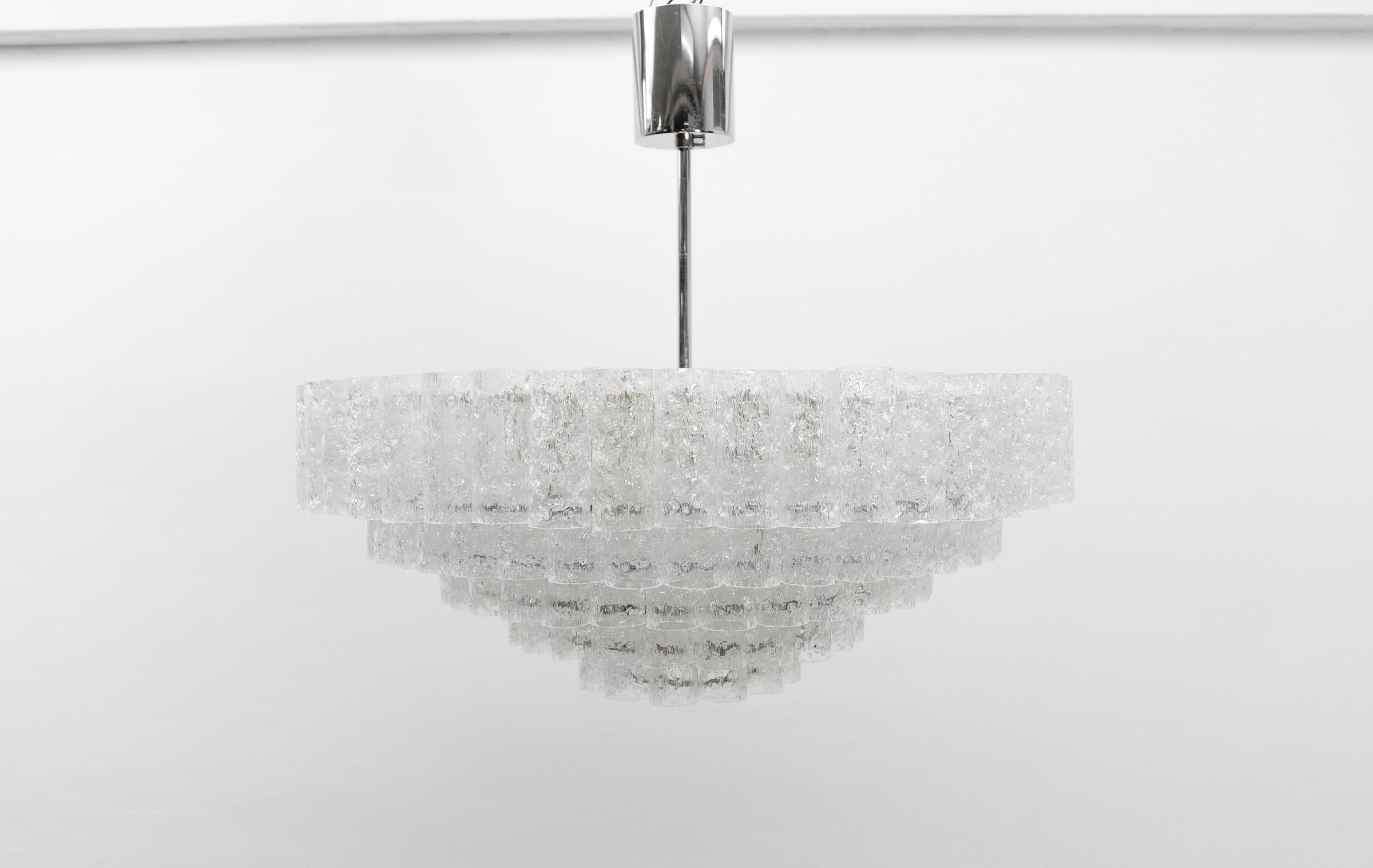 Ce lustre à cinq niveaux a été réalisé par Doria Leuchten. Elle comporte 143 éléments en verre et 9 prises E14.

Si vous avez d'autres questions, je me tiens à votre disposition.

Fonctionne de 110V à 230V dans tous les pays.

Livré sans ampoules.

