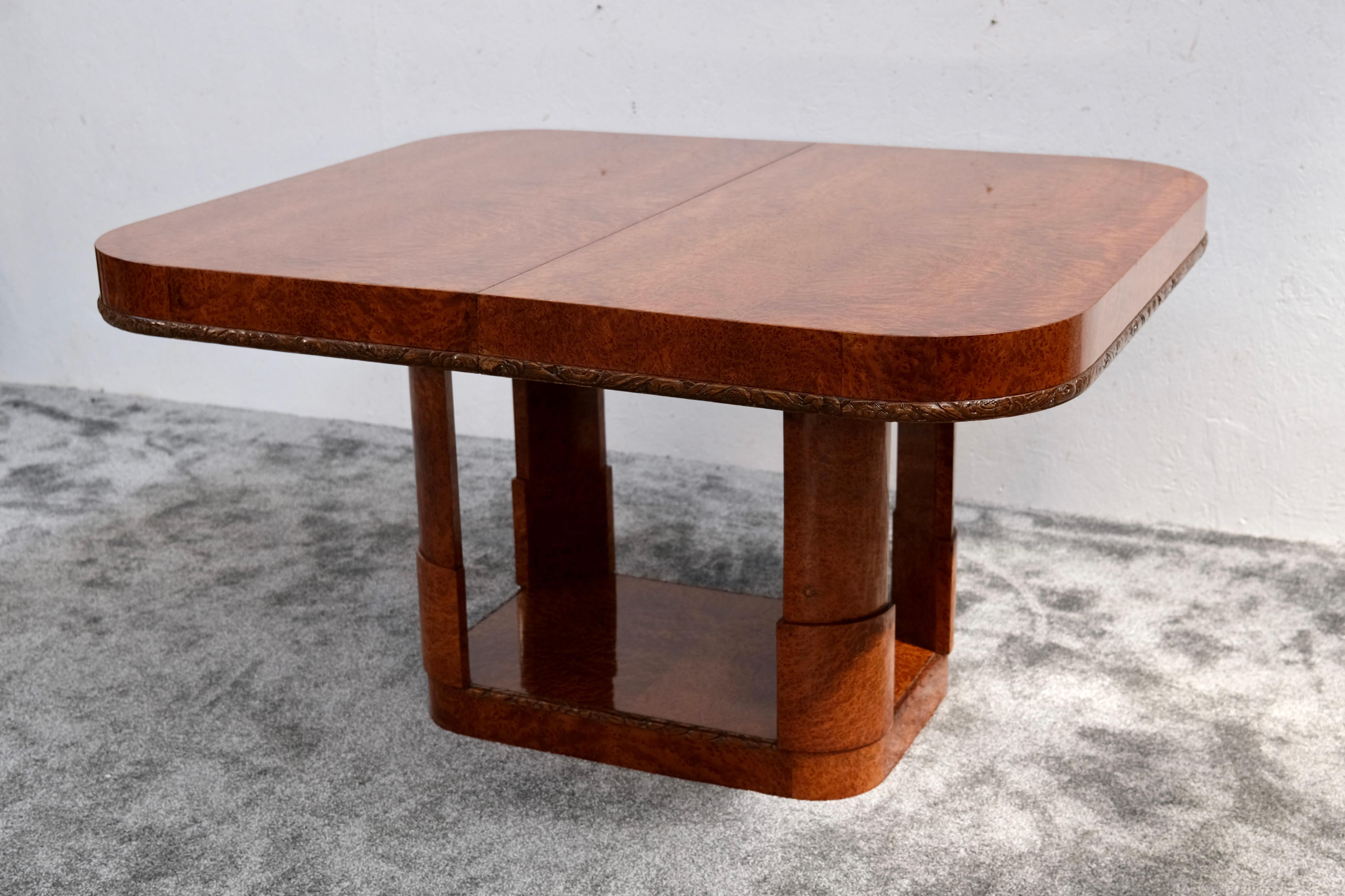 A striking Art Deco dining table from around 1930 – architecturally composed, expertly crafted, and rich in decorative detail.

This mostly rectangular table (130 × 110 × 75 cm  51.2 × 43.3 × 29.5 in) features a vivid Thuja burl veneer, beautifully