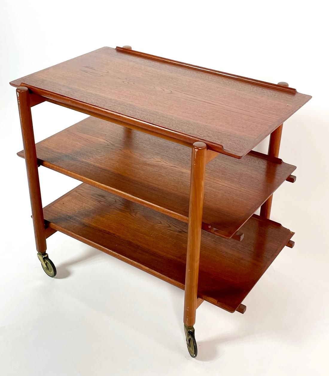 A 3-tier teak Danish modern bar cart / trolley on castors designed by Poul Hundevad, Denmark, circa 1960. Versatile configuration featuring a 3 tray design, 2 removable for serving or 1 may be attached to top level extending work or display
