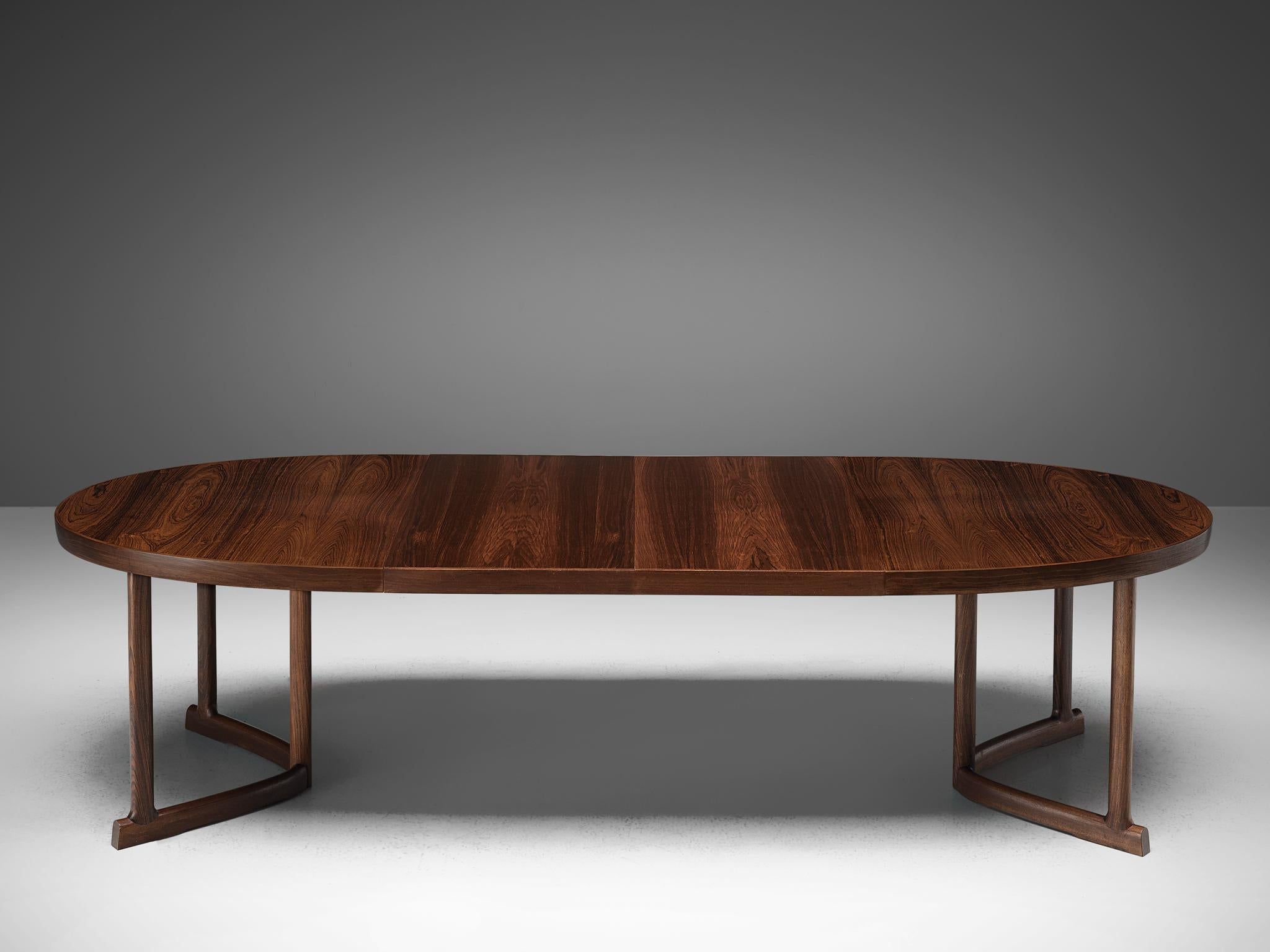 Extendable dining table, rosewood, Denmark, 1960s.

Large extendable oval dining table. The table has a striking tabletop with beautifully grained rosewood veneer placed in parallel lines. On both sides of the table it has three legs that are