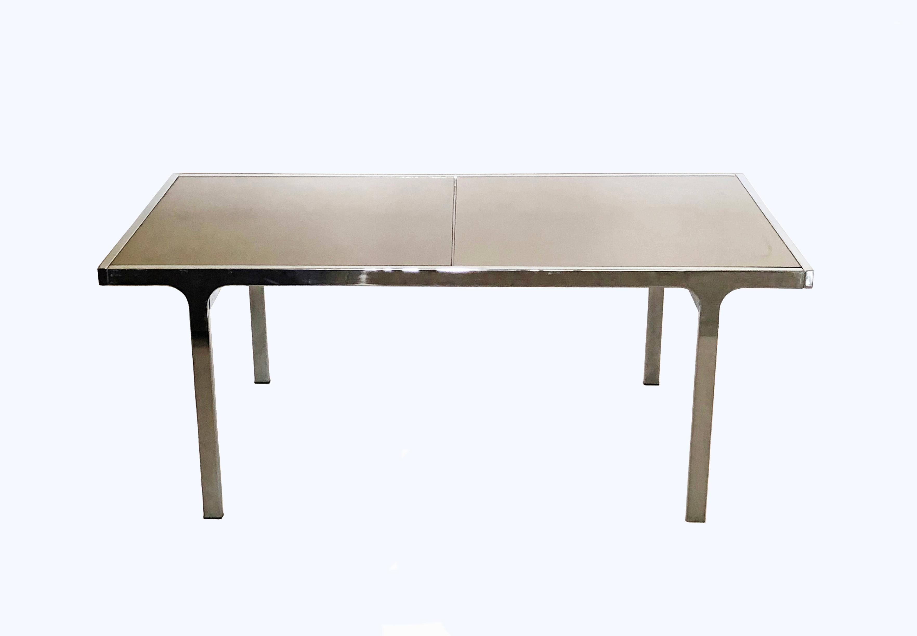 Chrome-plated steel, expandable dining table by Pierre Cardin for Dillingham with smoked bronze mirrored glass tops. The table has a concealed leaf in the center allowing for a 20 inch extension in length, to a total of 94 inches. Seats six