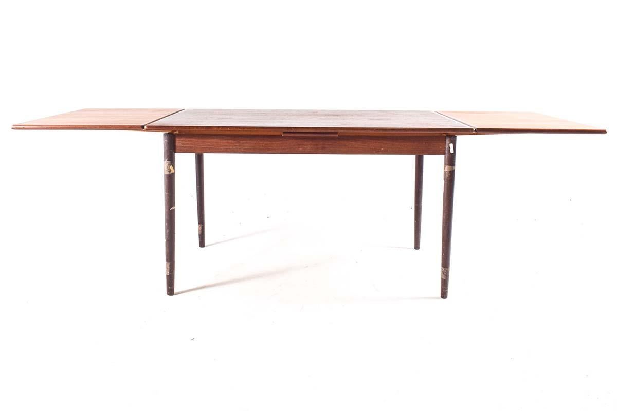 Immerse yourself in the timeless elegance of mid-century design with this exquisite rectangular dining table crafted from teak wood. This table exudes an aura of understated sophistication, boasting clean lines and a minimalist silhouette that