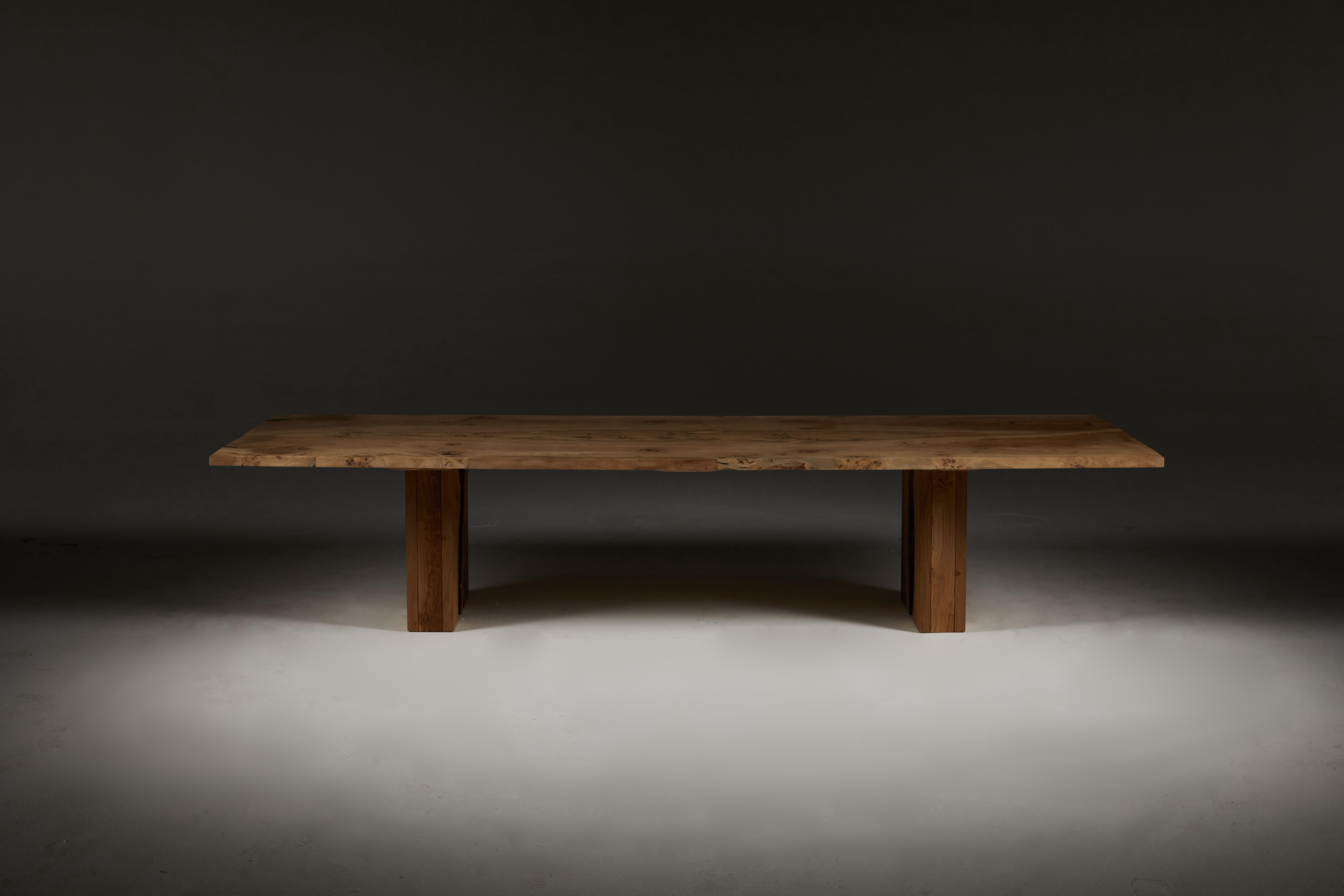 Extendable solid oak table with a central brown oak full-width slab inset into the table top.
The tabletop sits on two curved trapeze legs that are removable for transport. 
The table in the images is 300 cm / 118