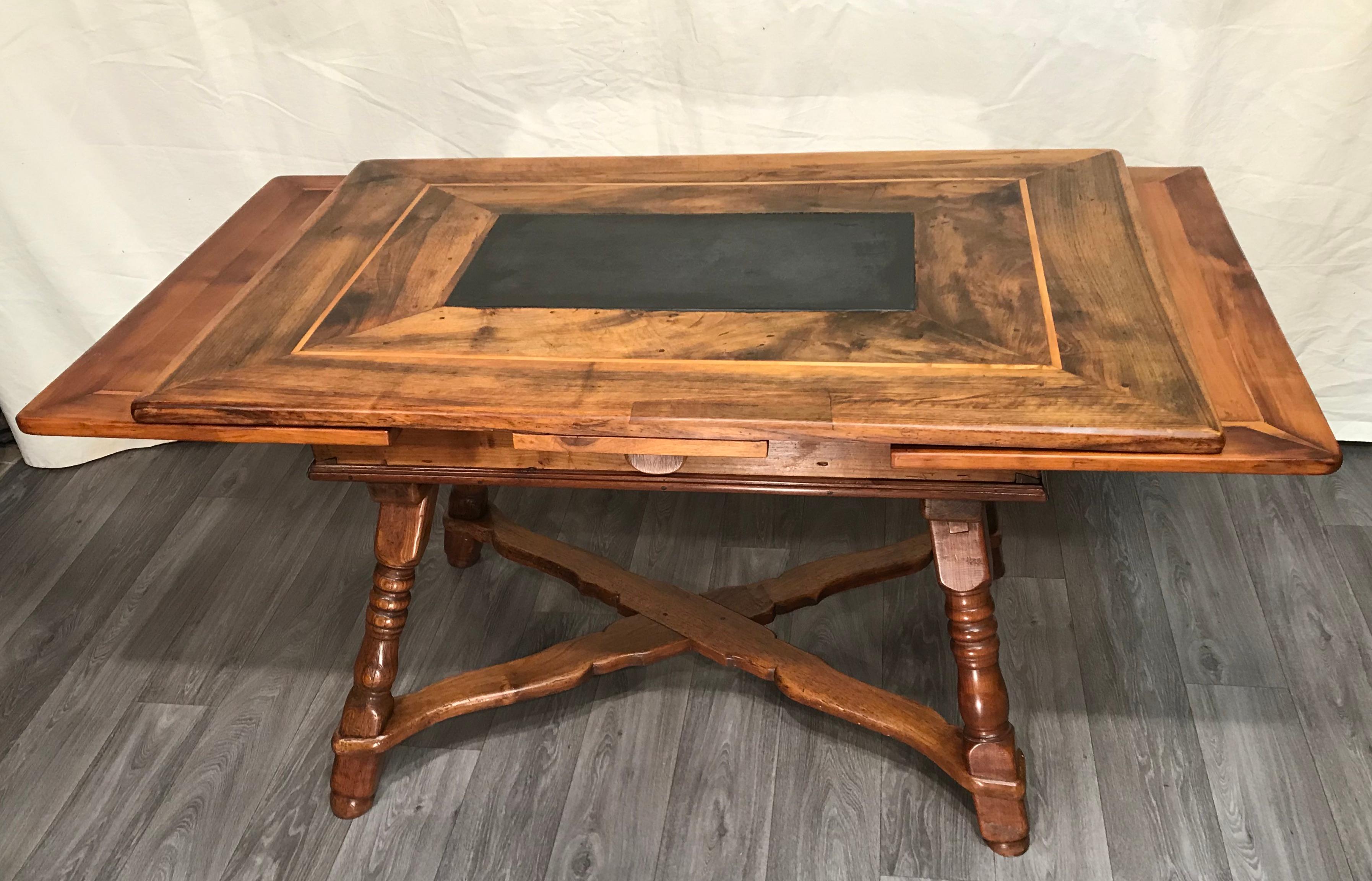 This extendable Swiss farm dining table of the 18th century is made of massive walnut. The center of the table has a slate slap. This is a typical detail of a Swiss rustic table of the 17th and 18th century. As a special feature this table is