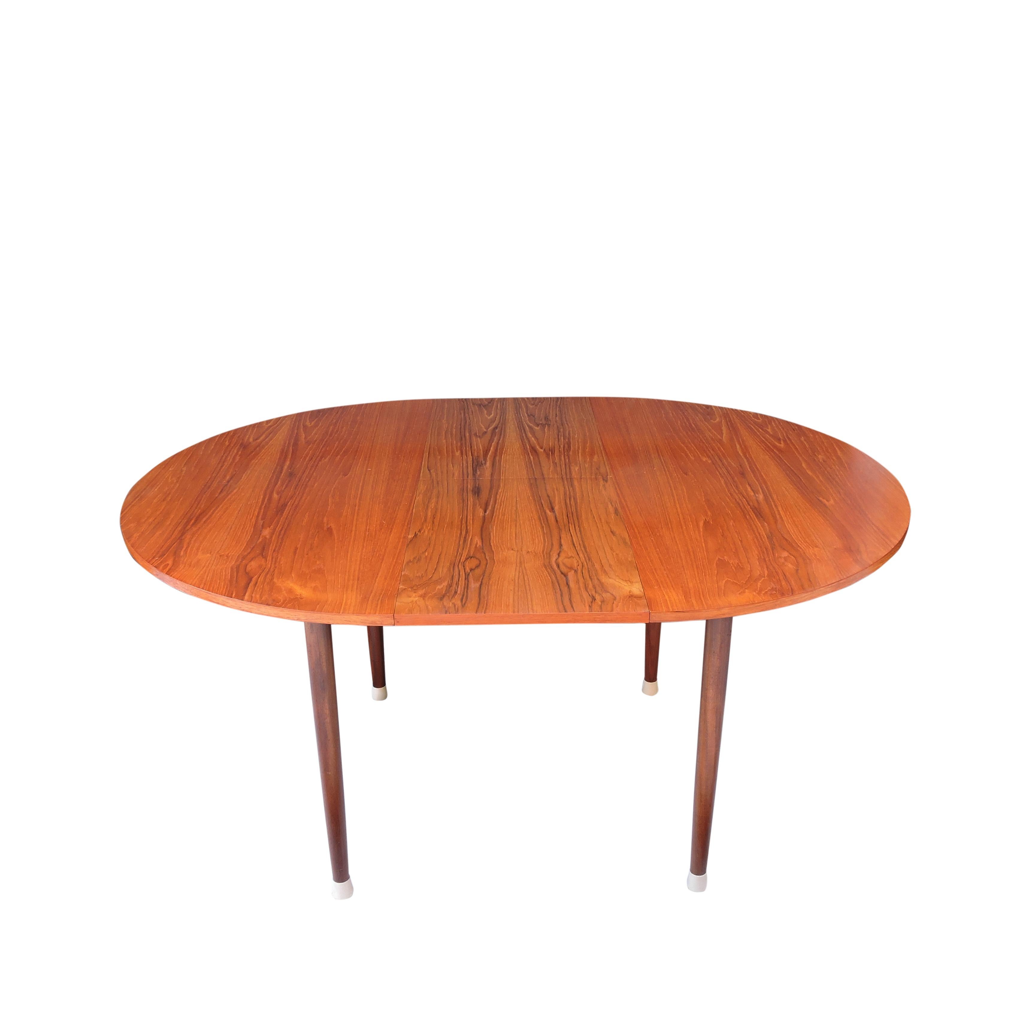 This 1960s extendable teak dining table features tapered legs on white rubber stoppers.