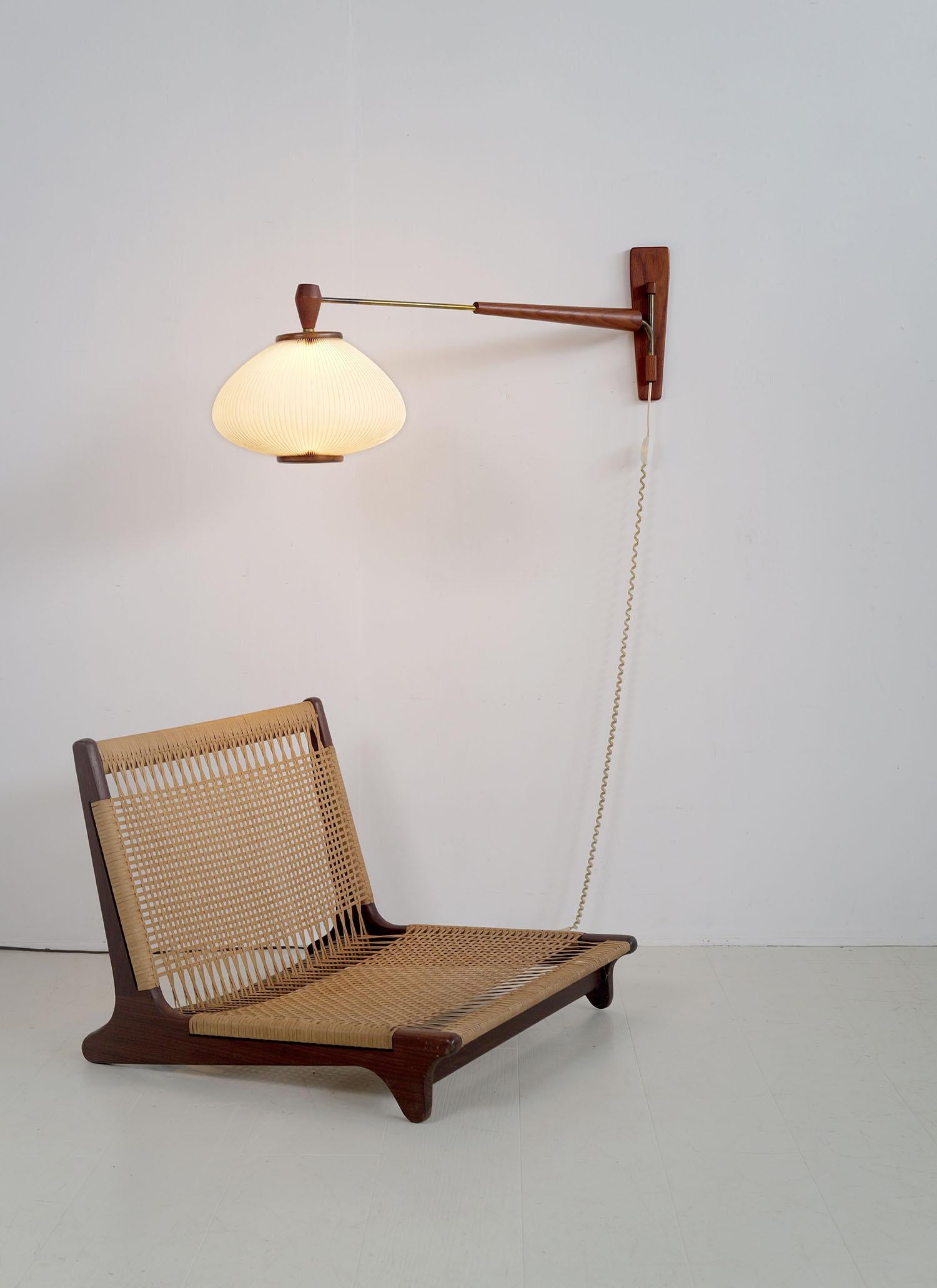 Extendable teak and brass wall lamp attributed to Maison Rispal, France, 1960. The pleated rhodoid shade is encircled by a wooden frame. The reflector arm slides and pivots. Beautiful light and very good condition.