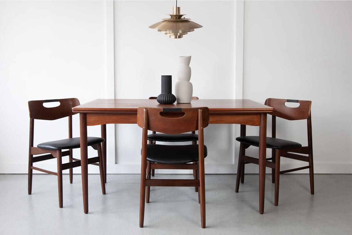 A neat and compact but comfortably sized rectangular Danish dining table in teak, with two extending leaves that pull out to accommodate larger gatherings. Elegant and simple in design with tapering legs and lovely grain detailing. 