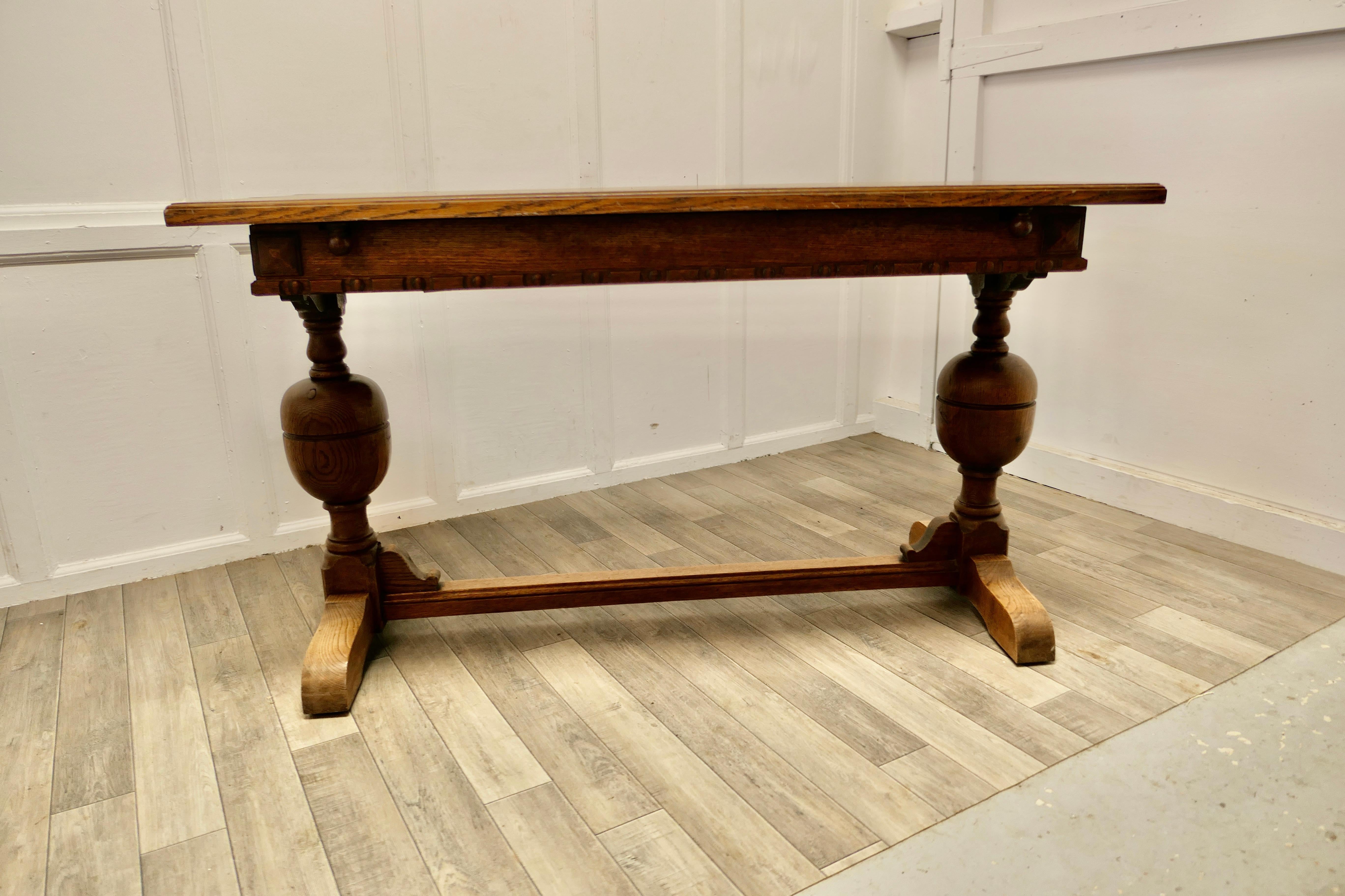 Extending oak refectory dining table.

This is a good sturdy table and at first glance it looks like an ordinary Oak refectory dining table with chunky bulbous legs and carved apron but it is narrower than normal. However this clever piece can be