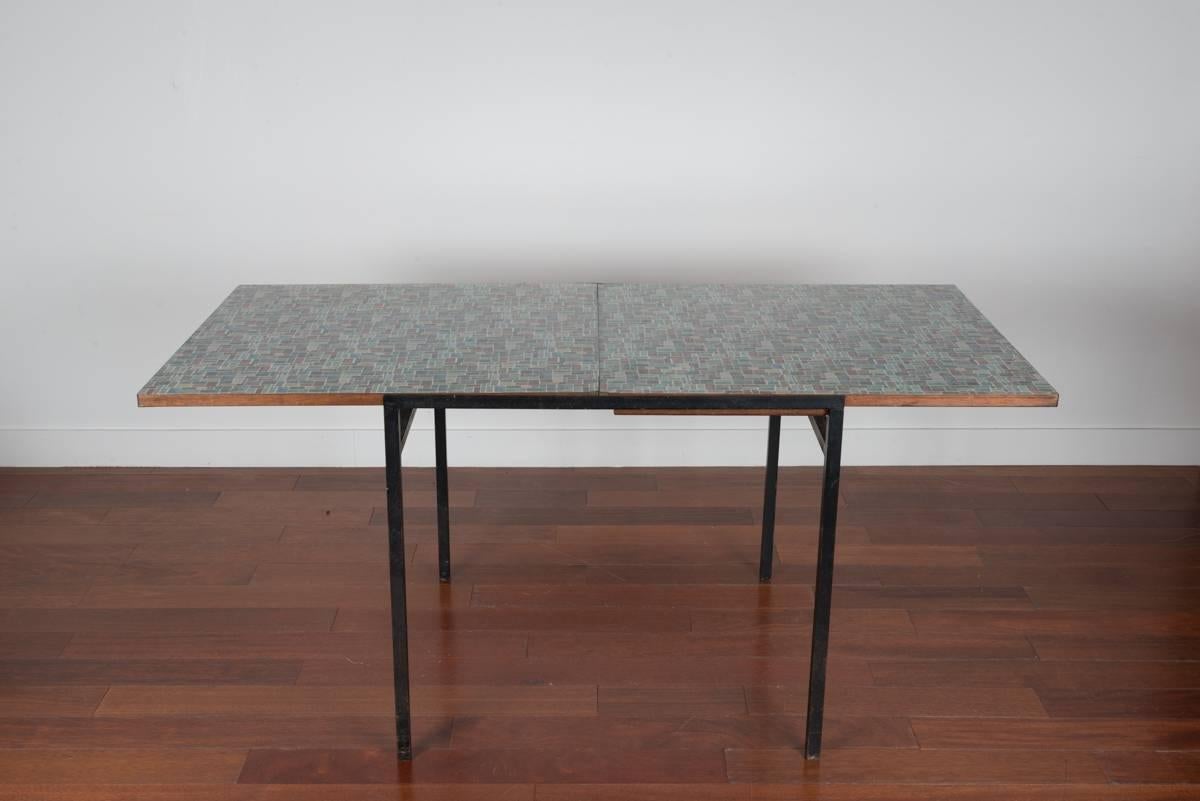 This table by the French designer Pierre Guariche has a tabletop extensible. The tabletop is made in ceramics designed by the artist Vieira Da Silva. Structure of the feet in black paint metal. Plate in wood and ceramics. The extensible tabletop