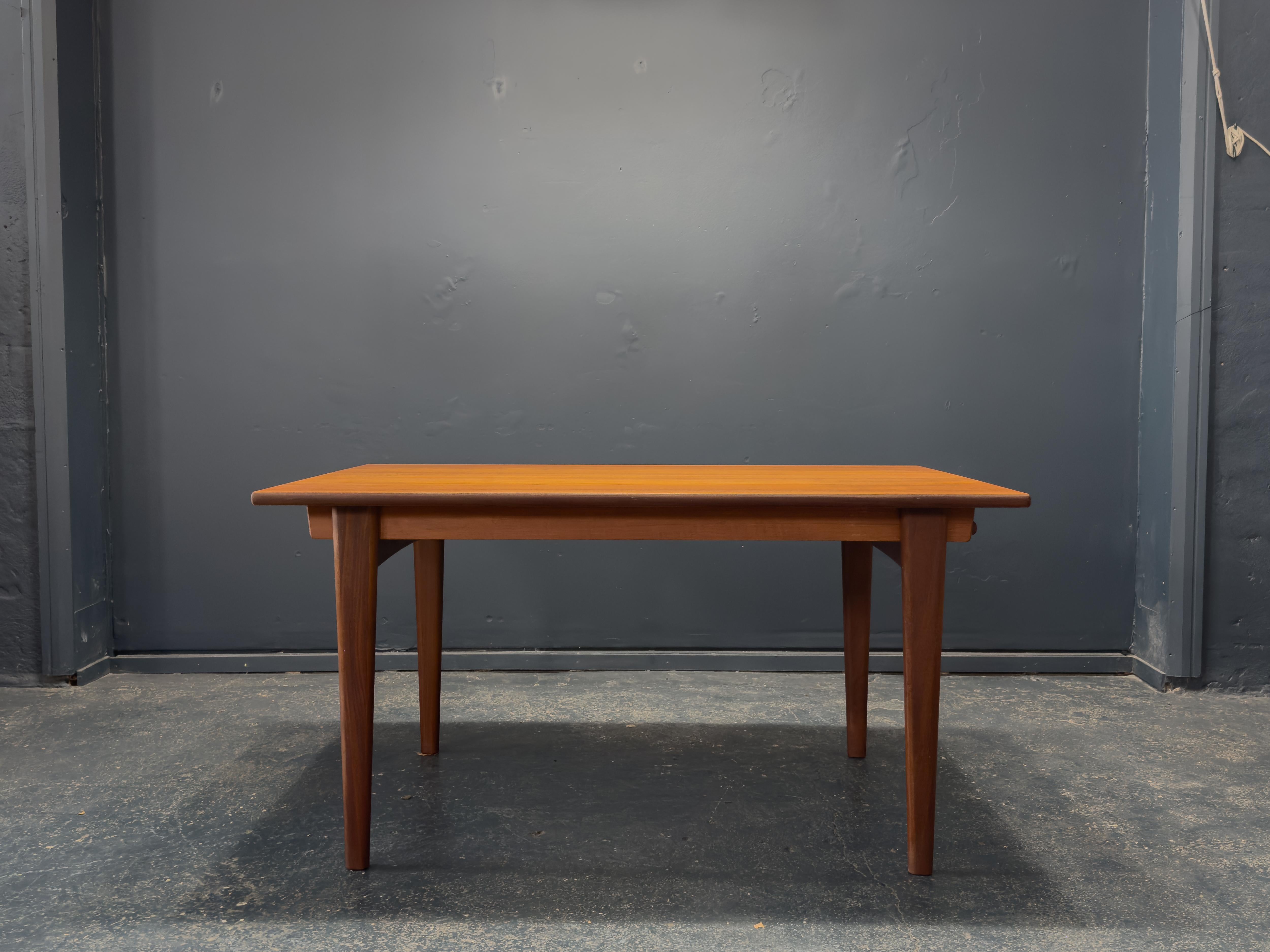 This elegant extending teak dining table is a beautifully engineered piece that blends streamlined design with practical functionality. Crafted from richly grained teak, the table showcases a warm, golden hue and rich grain pattern. 

Its compact