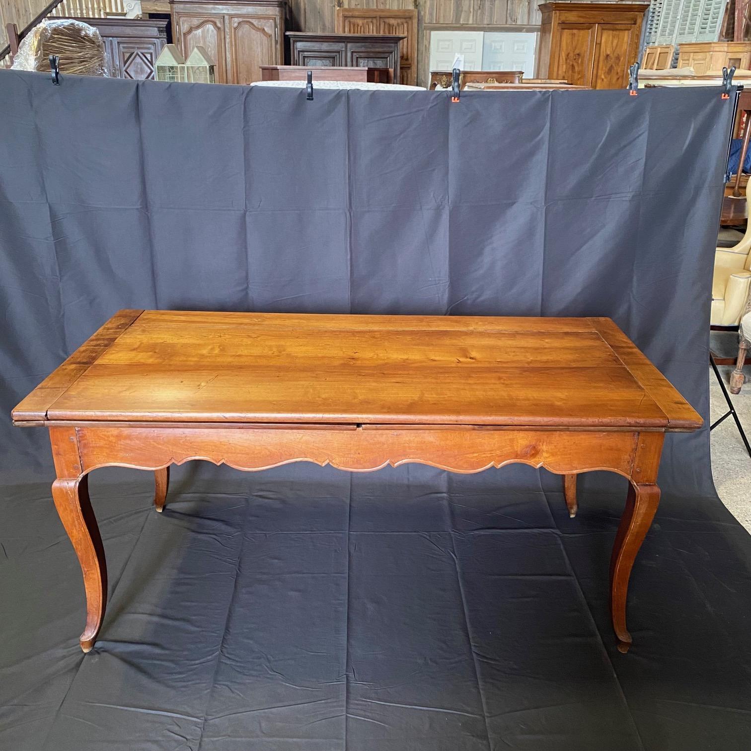 This elegant French farm dining table from Provence, France features two built in leaves, gracefully curved legs and a beautifully carved, scalloped apron. When closed, the table is 67 1/4  inches in length but can extend to just over 11 feet when
