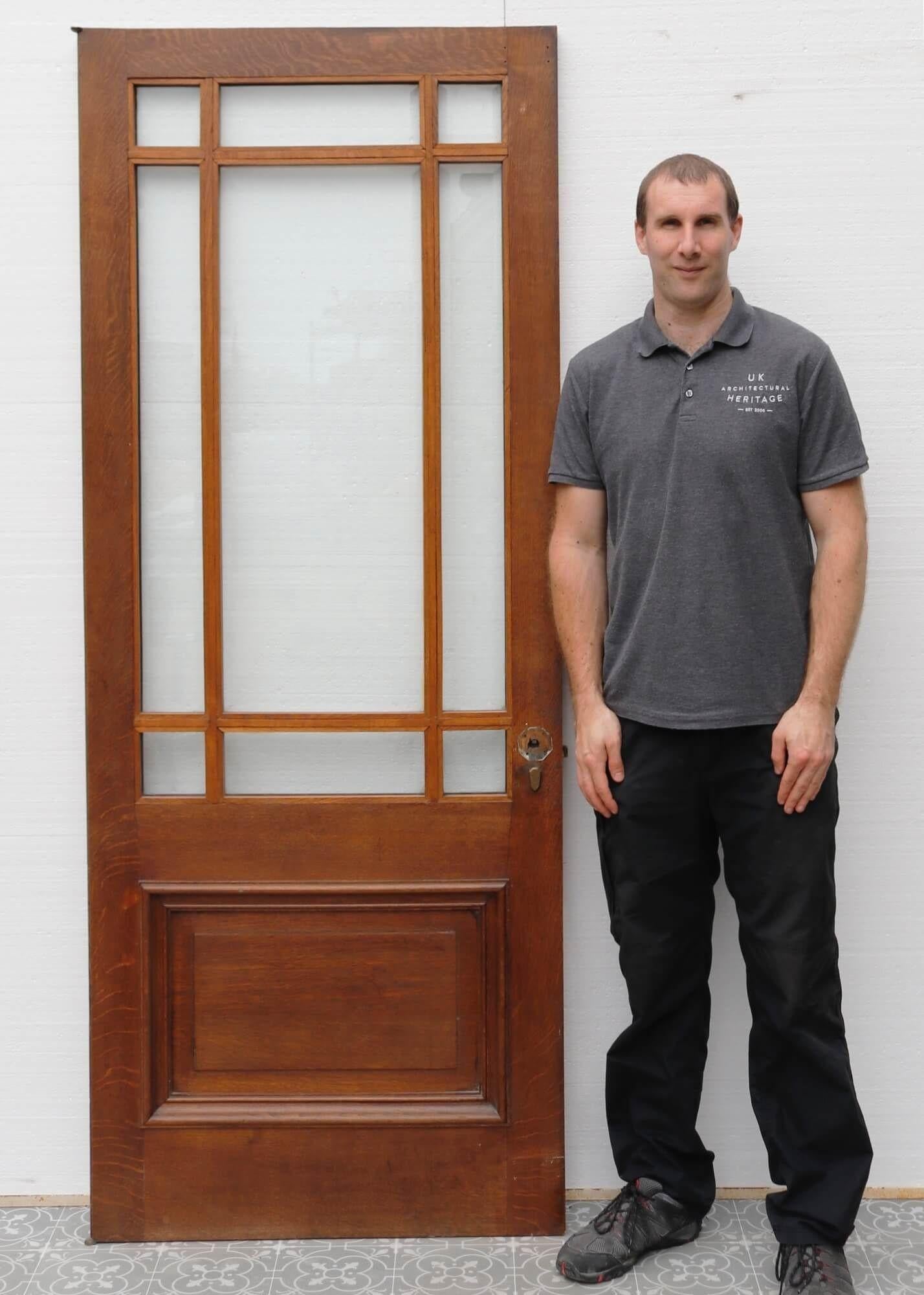 A smart Edwardian oak door suitable for internal or external use, dating from the early 1900s. This antique door features solid oak construction with a beautiful tone and grain, detailed with a single raised and fielded panel and gunstock style