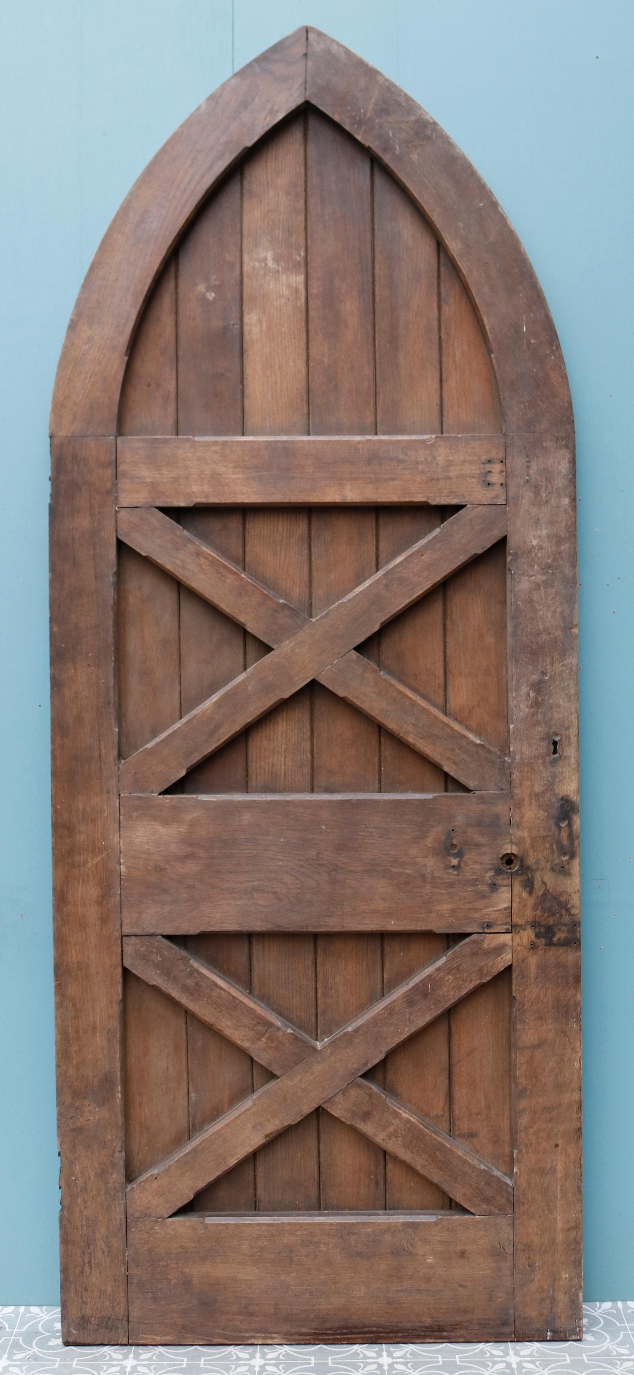 A Victorian Gothic style arched front door constructed from oak with decorative wrought iron hinges.