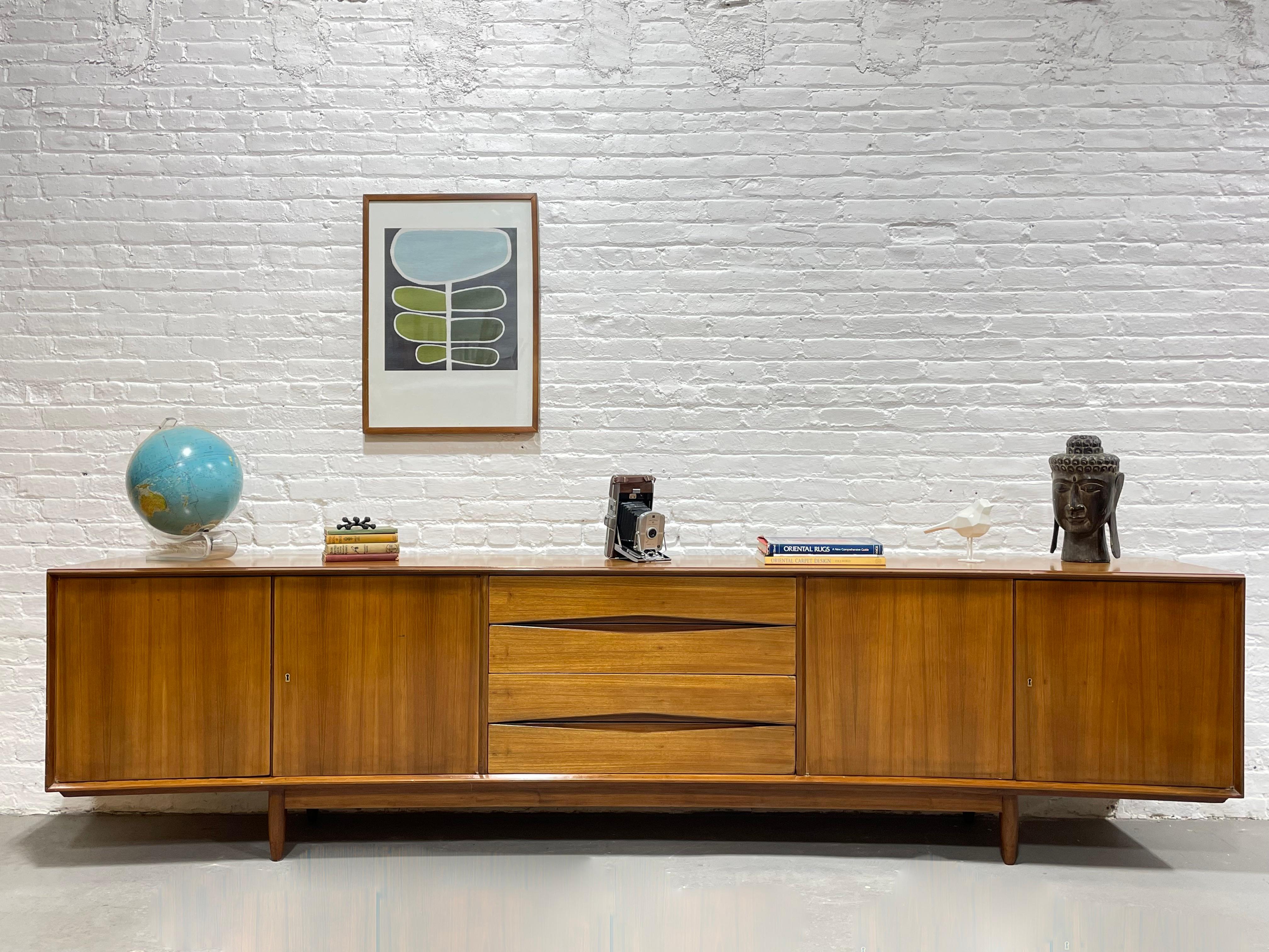 EXTRA LONG and just plain “EXTRA” in every sense. This monumental Mid Century Modern credenza is an absolute showstopper in a nearly impossible to find length of nearly 10 feet. This tremendous piece boasts a gentle curvature along the front, a