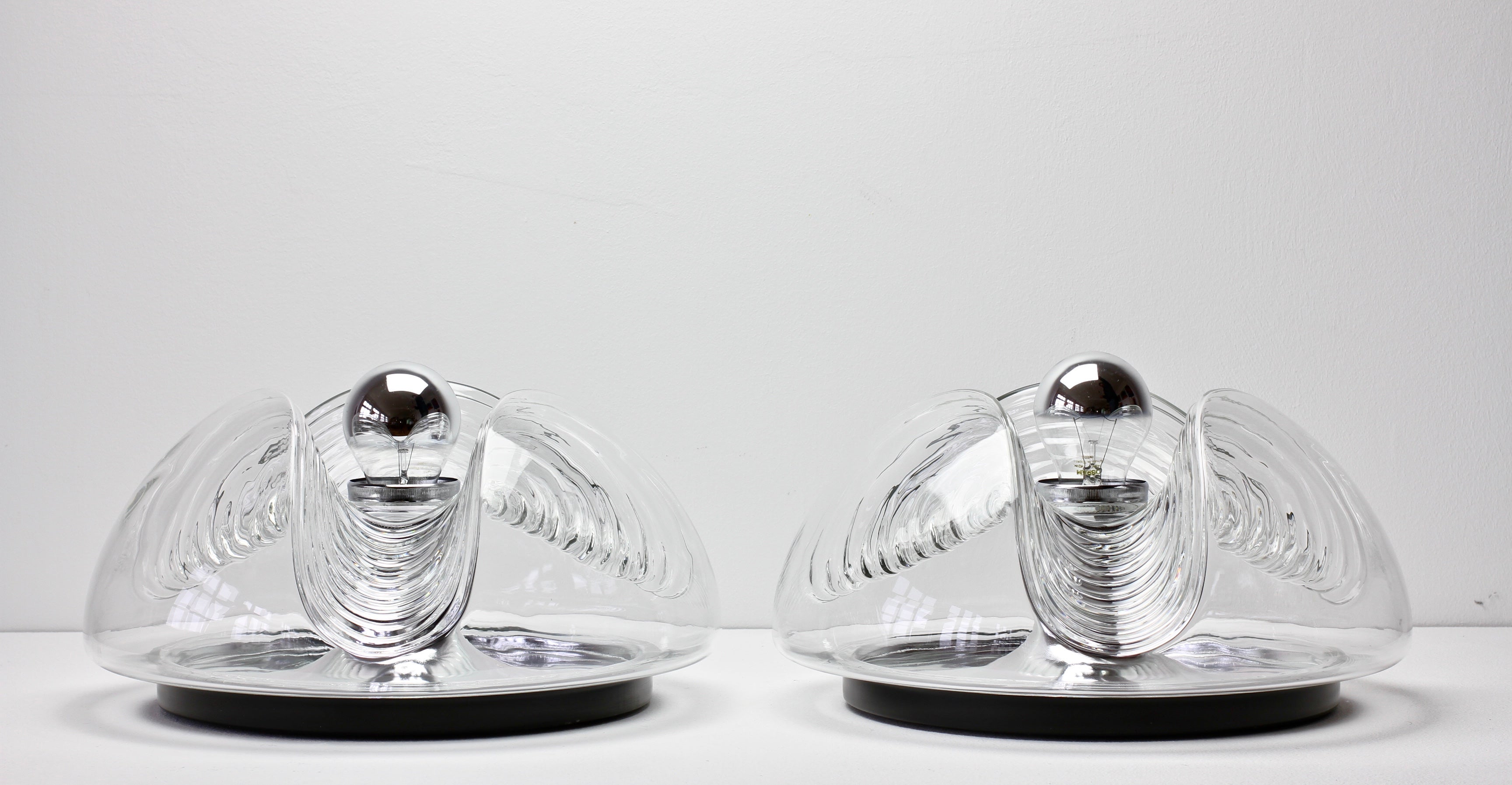 One of a pair of vintage Mid-Century Modern flush mount wall lights or sconces by Peill & Putzler in the 1970s. This is an absolutely classic piece of German design, featuring a clear glass globe shade with a waved/ribbed molded bubble form similar
