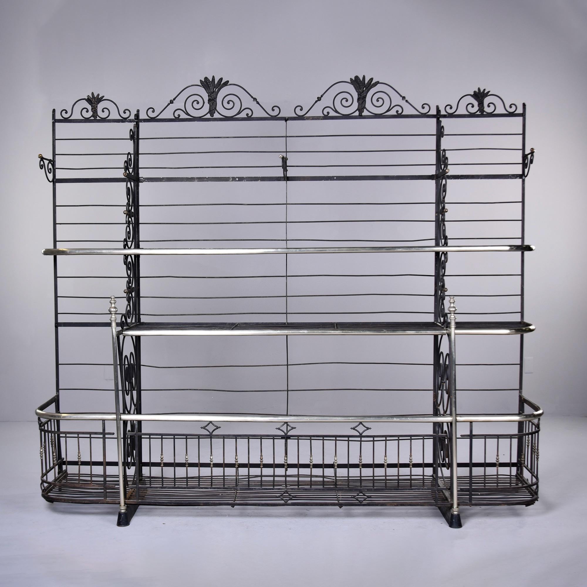 This extra large baker’s rack by Dubois of Lyon, France dates from the 1890s. Grand in scale, this iron and brass alloy rack is over 8 feet wide and 7 feet tall. It has three large open bins at the bottom with two shelf tiers above. Intricate scroll