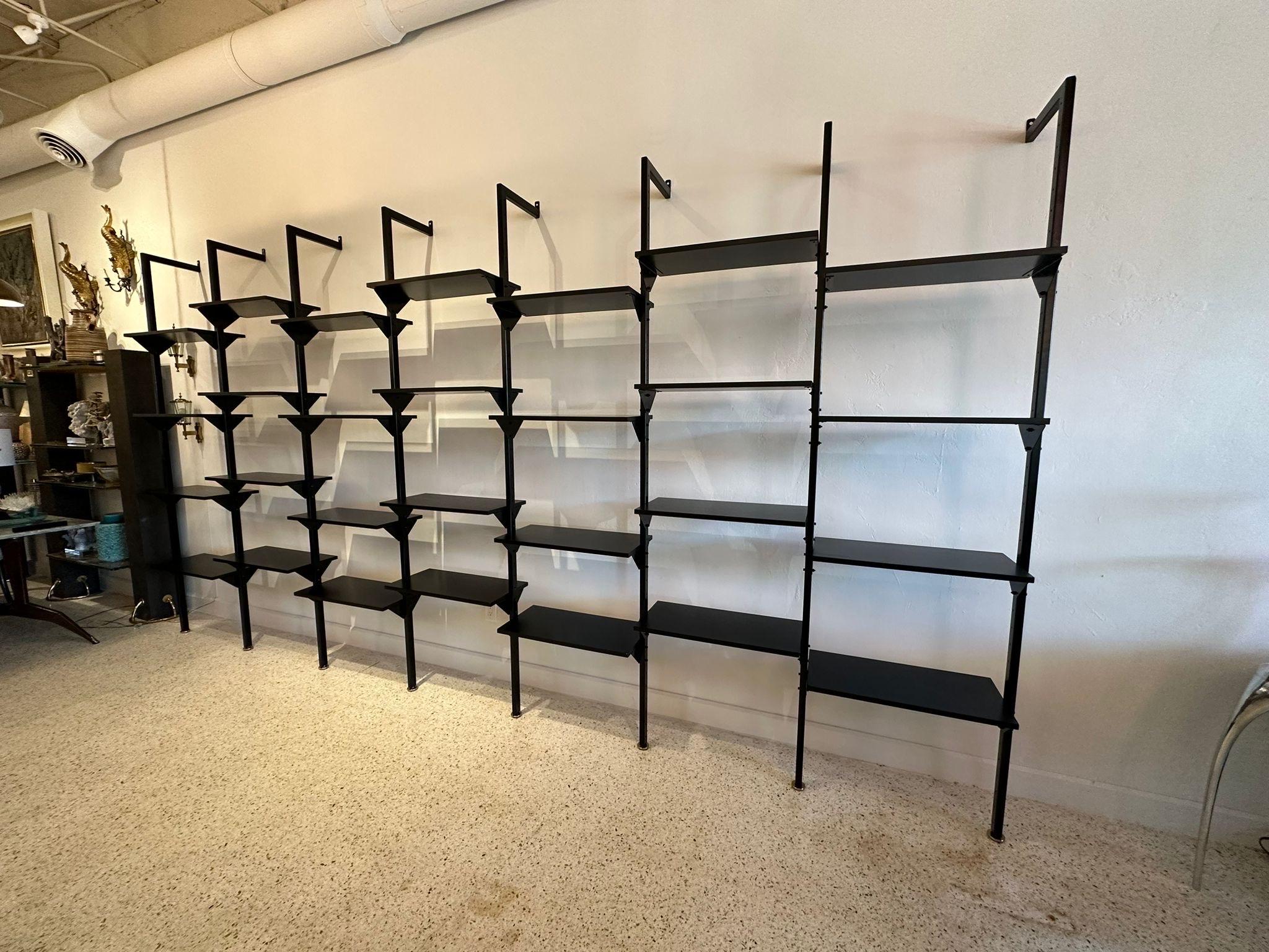 Rare Industrial Italian wall-mounted library or shelving system that is completely customize-able to your design needs. A very long shelving unit fitted with eight (8) powder coated metal posts for SEVEN (7) sections. Posts have gold plated