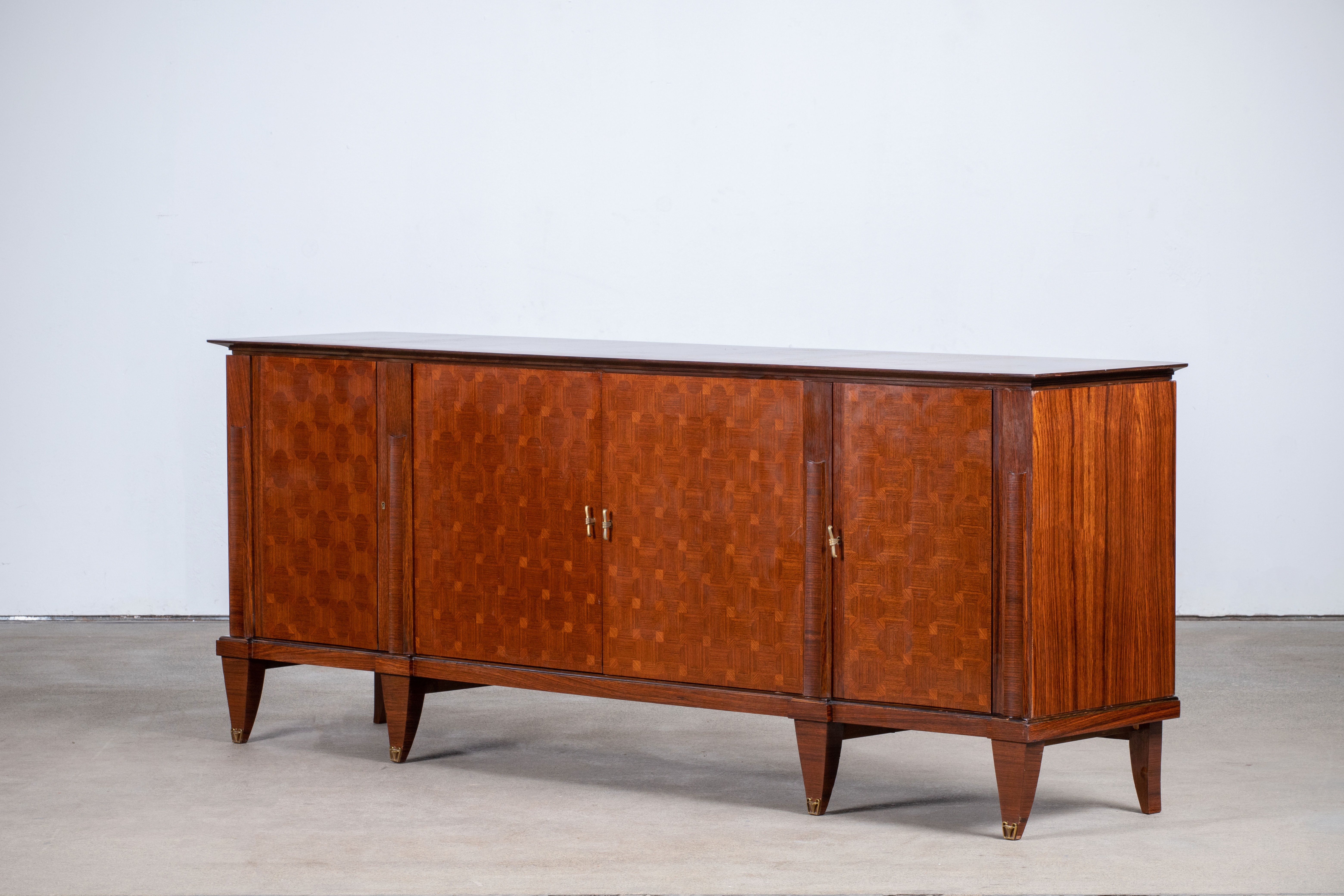 French Art Deco sideboard, credenza, with bar cabinet. The sideboard features stunning Macassar wood grain and rich pattern. It offers ample storage, with shelves and a column of drawers. The case rests on tall tapered legs with brass details. A