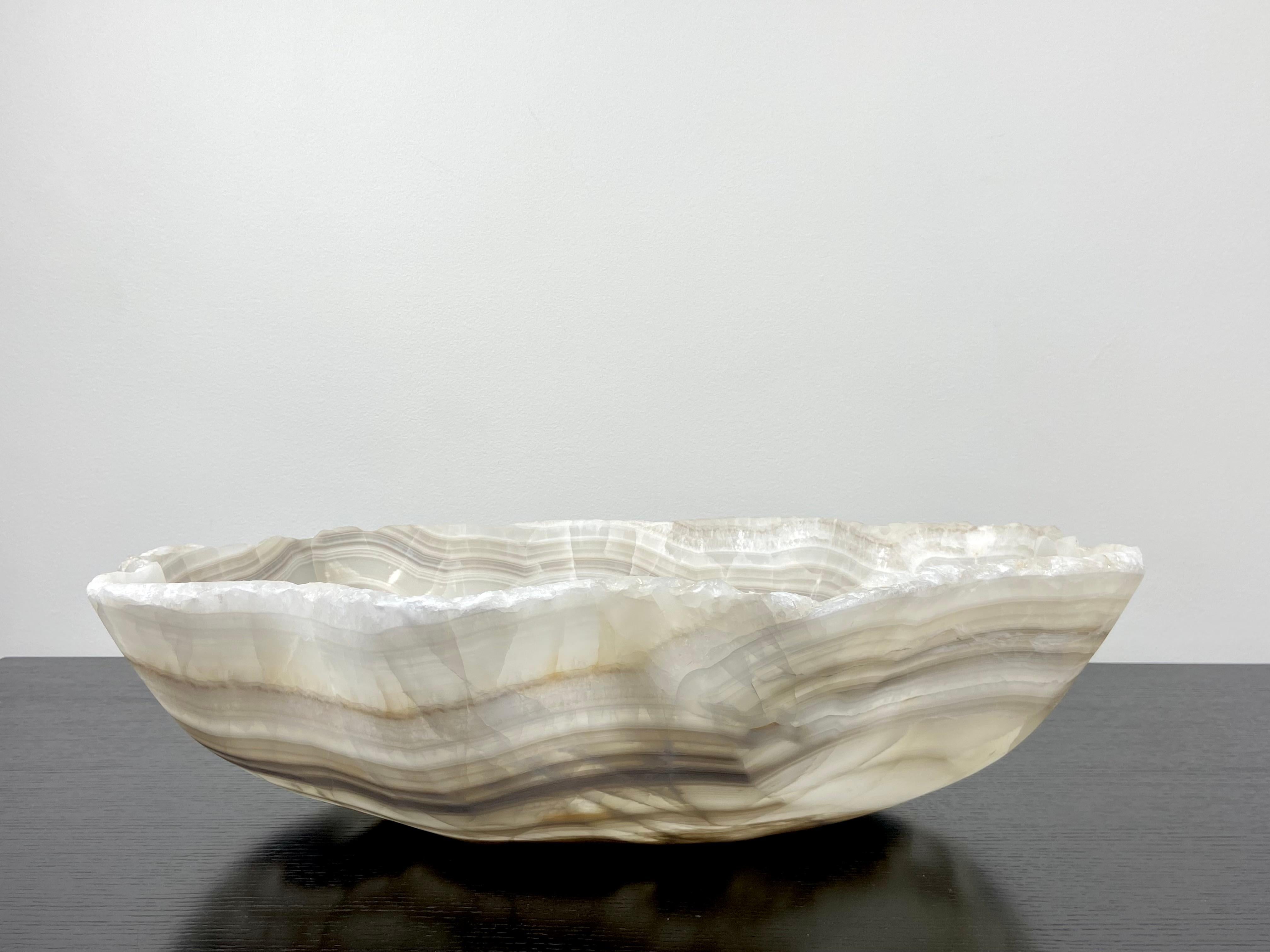 An extra large onyx bowl with banded stripes of grey and white. This one of a kind organically oval decorative vessel is meticulously hand-carved from a single piece of onyx by skilled artists to reveal its' inherent characteristics like the